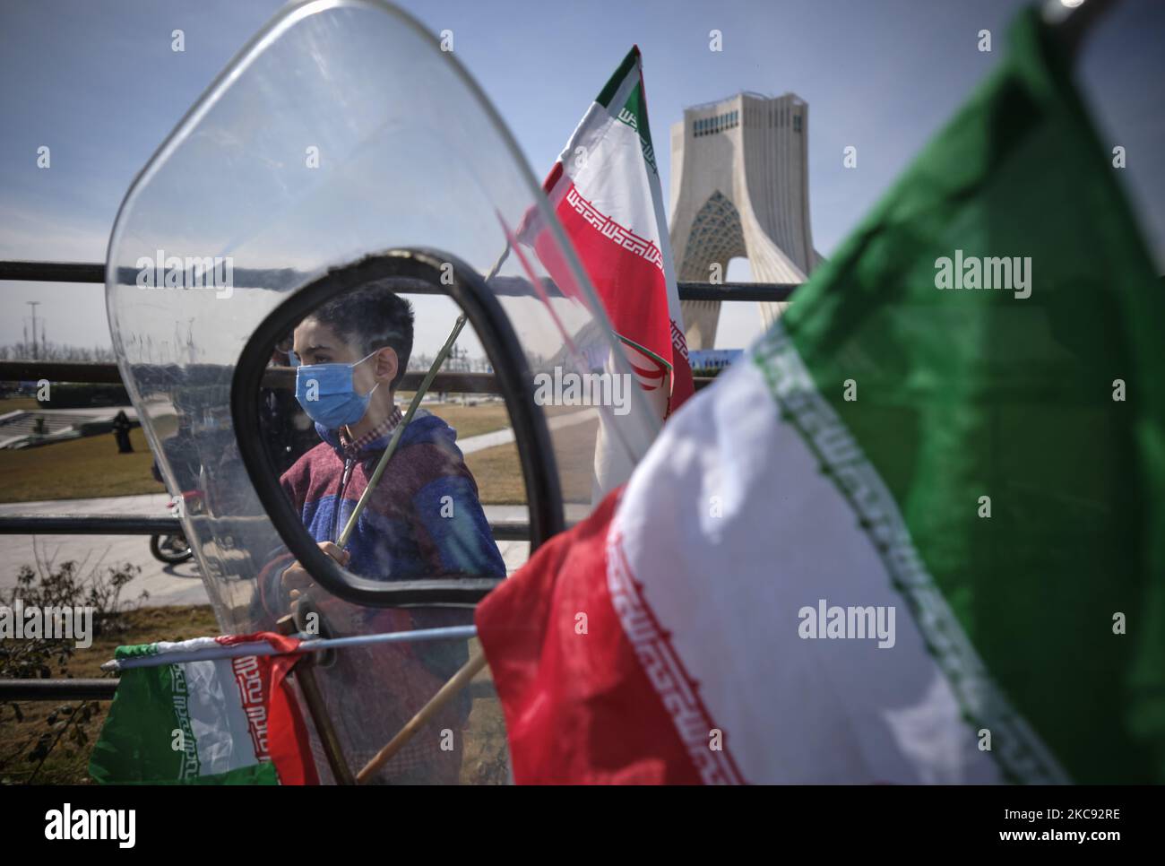 Ein iranischer Junge hält eine iranische Flagge während einer Kundgebung zum Gedenken an den 42.. Jahrestag des Sieges der Islamischen Revolution, die mit Motorrädern inmitten des Ausbruchs der neuen Coronavirus-Krankheit (COVID-19) im Iran am 10. Februar 2021, am 10. Februar 2021, auf dem Azadi-Platz (Freiheit) in Teheran stattfand. (Foto von Morteza Nikoubazl/NurPhoto) Stockfoto