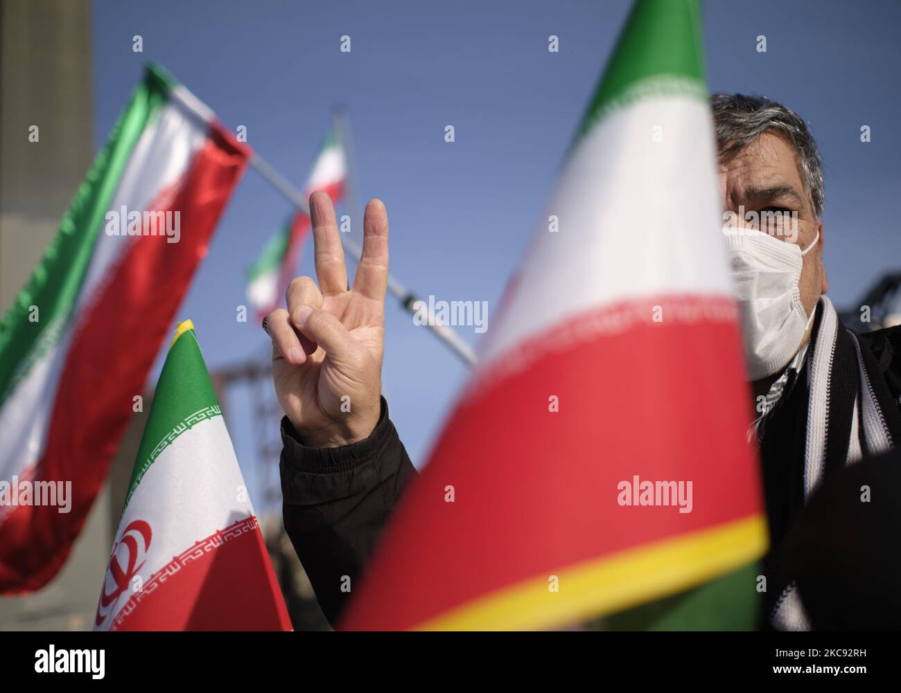 Ein Iraner mit einer schützenden Gesichtsmaske blinkt ein Siegeszeichen, während er neben iranische Flaggen sitzt, während er an einer Kundgebung zum Gedenken an den 42.. Jahrestag des Sieges der Islamischen Revolution teilnimmt. Die am 10. Februar 2021, am 10. Februar 2021, auf dem Imam Hussein Platz im Süden Teherans, mit Motorrädern während des Ausbruchs der neuen Coronavirus-Krankheit (COVID-19) im Iran stattfand. (Foto von Morteza Nikoubazl/NurPhoto) Stockfoto