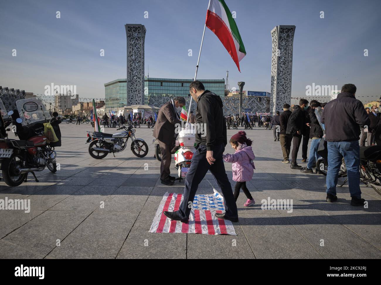 Ein Iraner und seine junge Tochter gehen auf der US-Flagge, während sie an einer Kundgebung zum Gedenken an den 42.. Jahrestag des Sieges der Islamischen Revolution teilnehmen. Die am 10. Februar 2021, am 10. Februar 2021, auf dem Imam Hussein Platz im Süden Teherans, mit Motorrädern während des Ausbruchs der neuen Coronavirus-Krankheit (COVID-19) im Iran stattfand. (Foto von Morteza Nikoubazl/NurPhoto) Stockfoto