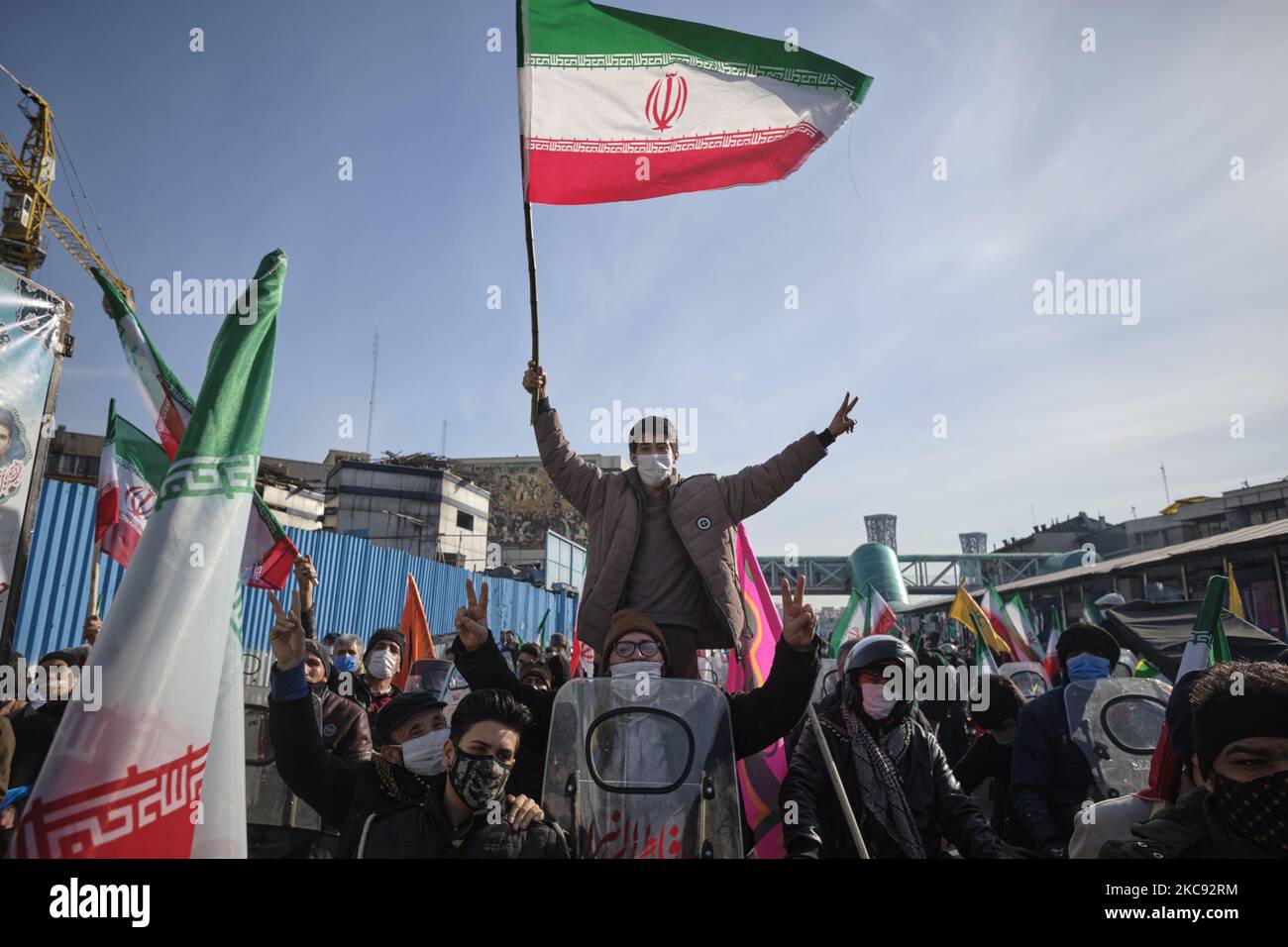 Ein Iraner mit einer schützenden Gesichtsmaske winkt eine iranische Flagge und blendet ein Siegeszeichen auf, während er auf einem Motorrad während einer Kundgebung zum Gedenken an den 42.. Jahrestag des Sieges der Islamischen Revolution steht, Die am 10. Februar 2021, am 10. Februar 2021, auf dem Imam Hussein Platz im Süden Teherans, mit Motorrädern während des Ausbruchs der neuen Coronavirus-Krankheit (COVID-19) im Iran stattfand. (Foto von Morteza Nikoubazl/NurPhoto) Stockfoto