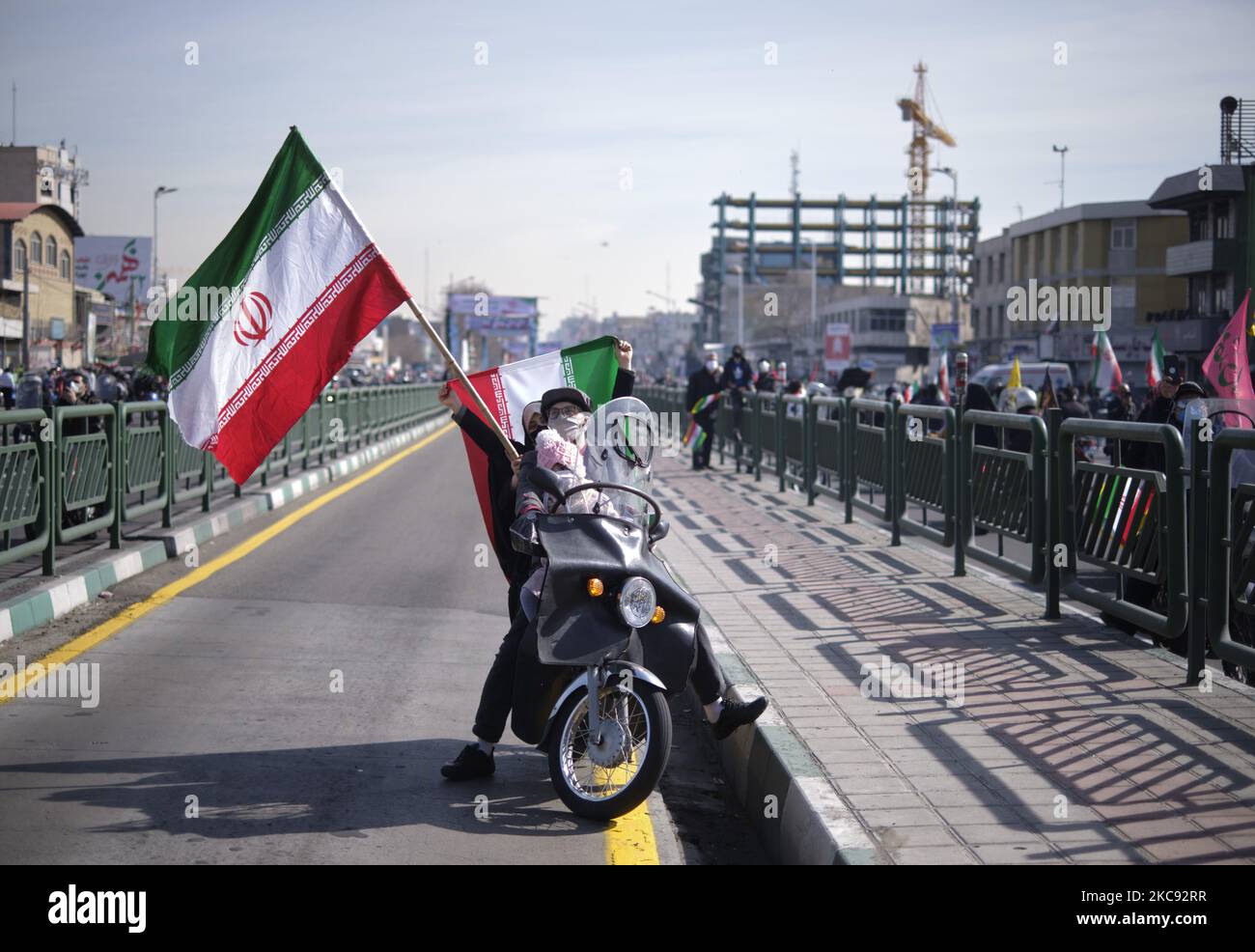 Ein Iraner und seine Frau winken Iran-Flaggen, während sie auf ihrem Motorrad sitzen, während sie auf einer Kundgebung zum Gedenken an den 42.. Jahrestag des Sieges der Islamischen Revolution Das fand am 10. Februar 2021, am 10. Februar 2021, in der Azadi (Freedom) Avenue in Teheran mit Motorrädern inmitten des Ausbruchs der neuen Coronavirus-Krankheit (COVID-19) im Iran statt. (Foto von Morteza Nikoubazl/NurPhoto) Stockfoto