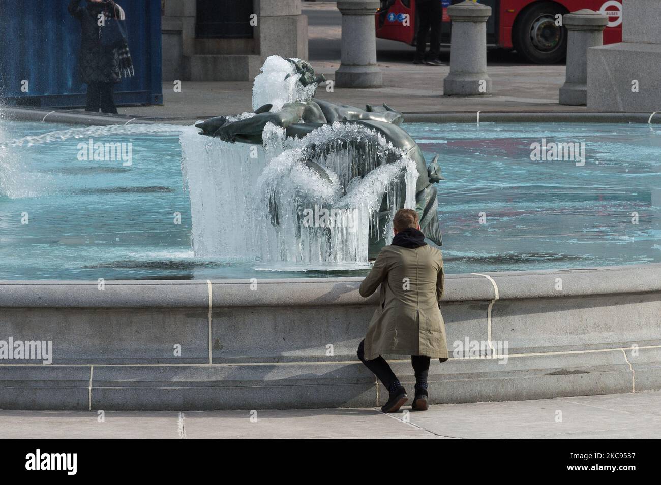 Ein Mann macht am 12. Februar 2021 in London, England, ein Foto einer gefrorenen Meerjungfrau-Statue im Brunnen am Trafalgar Square an einem kalten Wintertag, an dem England unter der dritten Sperre bleibt, um die Covid-19-Infektionsraten zu reduzieren. (Foto von Wiktor Szymanowicz/NurPhoto) Stockfoto