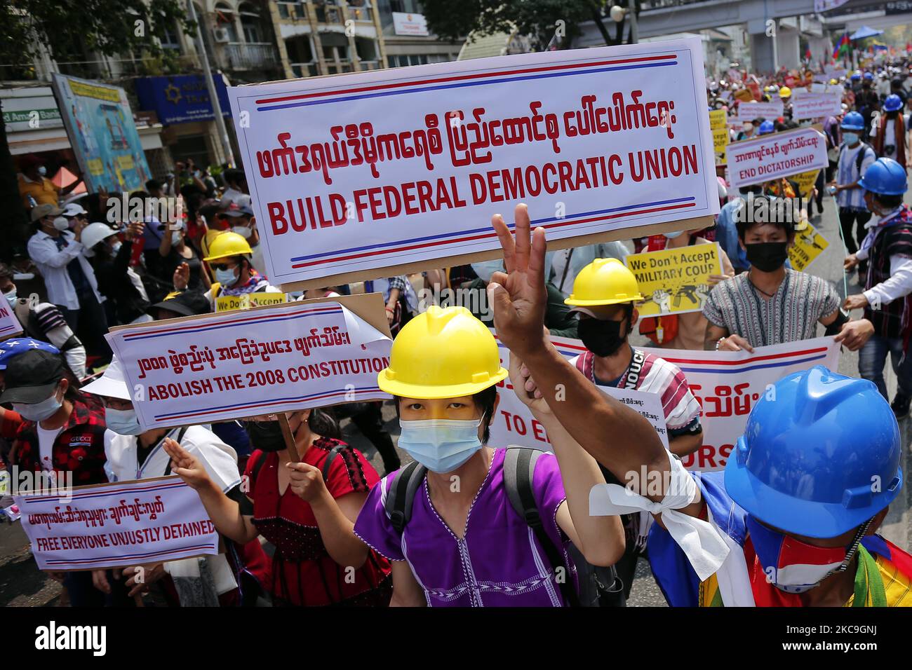 Demonstranten halten Plakate hoch und grüßen mit drei Fingern, während sie während einer Demonstration gegen den Militärputsch in Yangon, Myanmar, am 18. Februar 2021 marschieren. (Foto von Myat Thu Kyaw/NurPhoto) Stockfoto