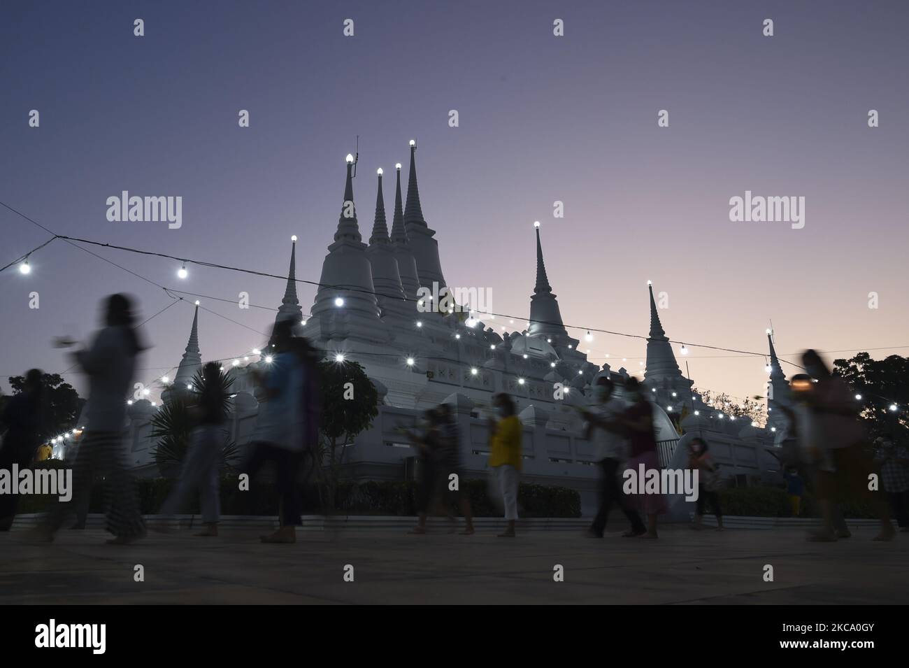 Menschen, die Blumen, Joss-Sticks und Kerzen für Gebete halten, gehen in einer Kreisprozession um das Kloster, um den Makha Bucha-Tag im Wat Asokaram-Tempel in der Provinz Samut Prakan, Thailand, am 26. Februar 2021 zu markieren. (Foto von Anusak Laowias/NurPhoto) Stockfoto