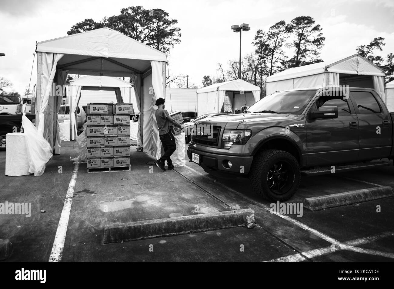 (ANMERKUNG DES HERAUSGEBERS: Bild wurde in Schwarz-Weiß umgewandelt) Freiwillige auf einem Gelände der Houston Food Bank im Freien arbeiten unermüdlich daran, Nahrungsmittel an Bedürftige zu verteilen, während die Stromkrise der letzten Woche am Nachmittag des Freitags, dem 26. Februar 2021, andauerte. (Foto von Reginald Mathalone/NurPhoto) Stockfoto