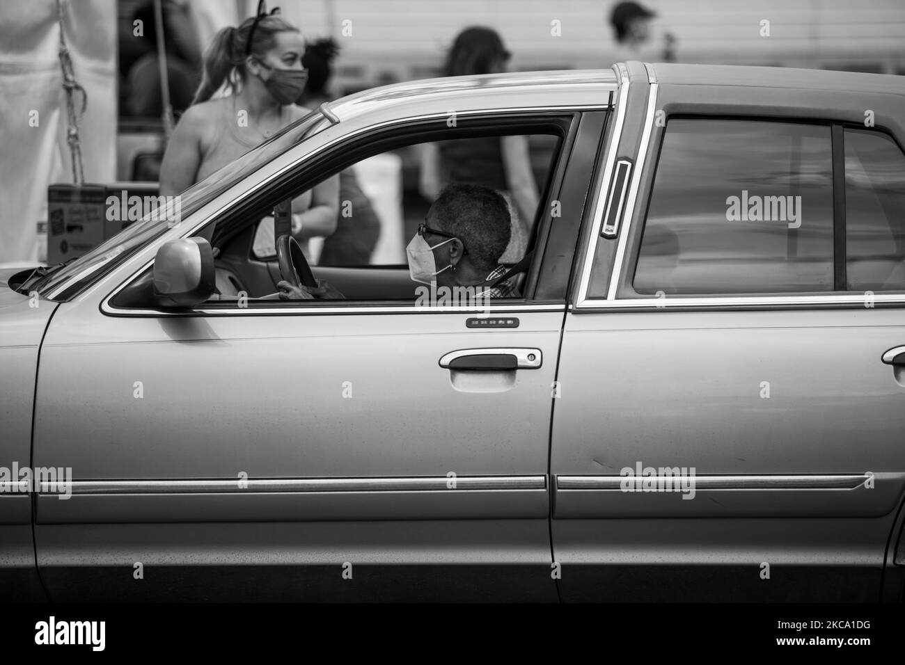 (ANMERKUNG DER REDAKTION: Bild wurde in Schwarz-Weiß umgewandelt) Eine in Houston ansässige Person fährt am Freitag, dem 26. Februar 2021, in eine Houston Food Bank, während Freiwillige ihr Auto mit Essen beladen. (Foto von Reginald Mathalone/NurPhoto) Stockfoto