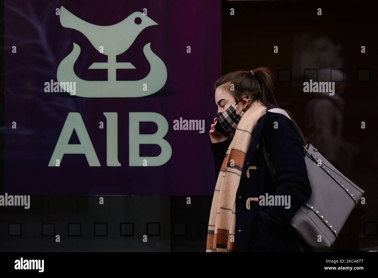 Eine Frau mit Gesichtsmaske kommt während der COVID-19-Sperre auf Level 5 an einer AIB-Niederlassung im Stadtzentrum von Dublin vorbei. Die Bank of Ireland gab heute die Schließung von 103 Filialen in ganz Irland bekannt, da die Beschleunigung des digitalen Bankwesens nun seinen „kritischen Punkt“ erreicht hat. Insgesamt werden 88 Filialen in der Republik Irland schließen, die 169 verlassen werden, und 15 Filialen in Nordirland werden die 13 schließen. Am Montag, den 1. März 2021, in Dublin, Irland. (Foto von Artur Widak/NurPhoto) Stockfoto