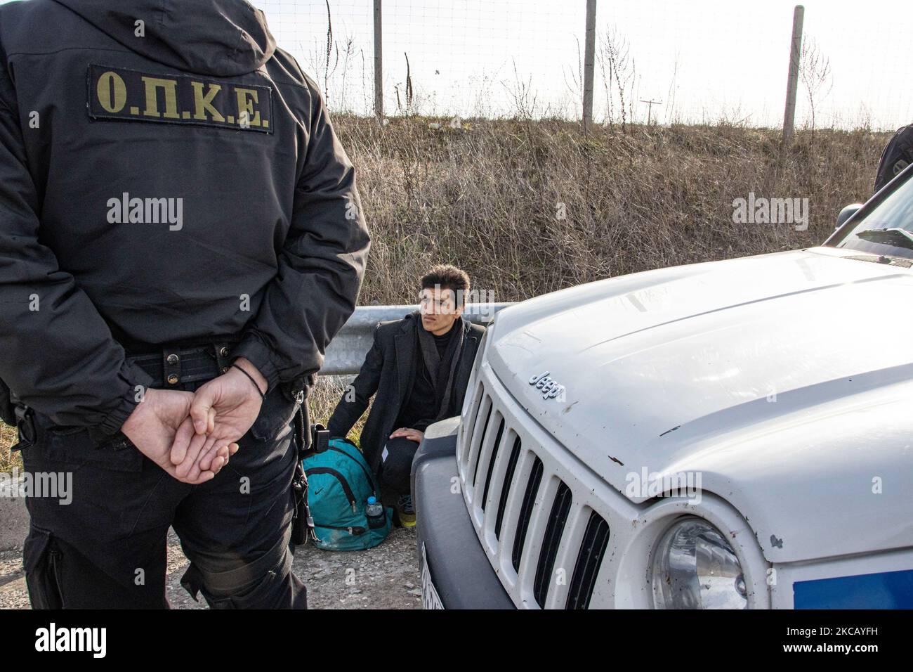 Auf der Autobahn in der Nähe der Stadt Orestiada in der Region Evros, Thrakien, in Griechenland, befinden sich Polizeiautos und Polizeibeamte, die 2 Migranten ohne Papiere halten, einen aus Afghanistan und einen aus Afrika, die illegal die Grenzen der Türkei überquerten. Der Evros-Fluss oder Martisa oder Meric ist die südöstlichere Außengrenze der EU und des Schengen-Raums. Asylbewerber werden entlang der griechisch-türkischen Grenzen gefangen genommen, während sie versuchen, nach Griechenland und in die Europäische Union einzureisen. Die hellenische Polizei und Frontex-Truppen machen die Grenzpatrouille und nehmen täglich fest oder verhaften Migranten, Flüchtlinge und Schmuggler auf den griechischen Stockfoto