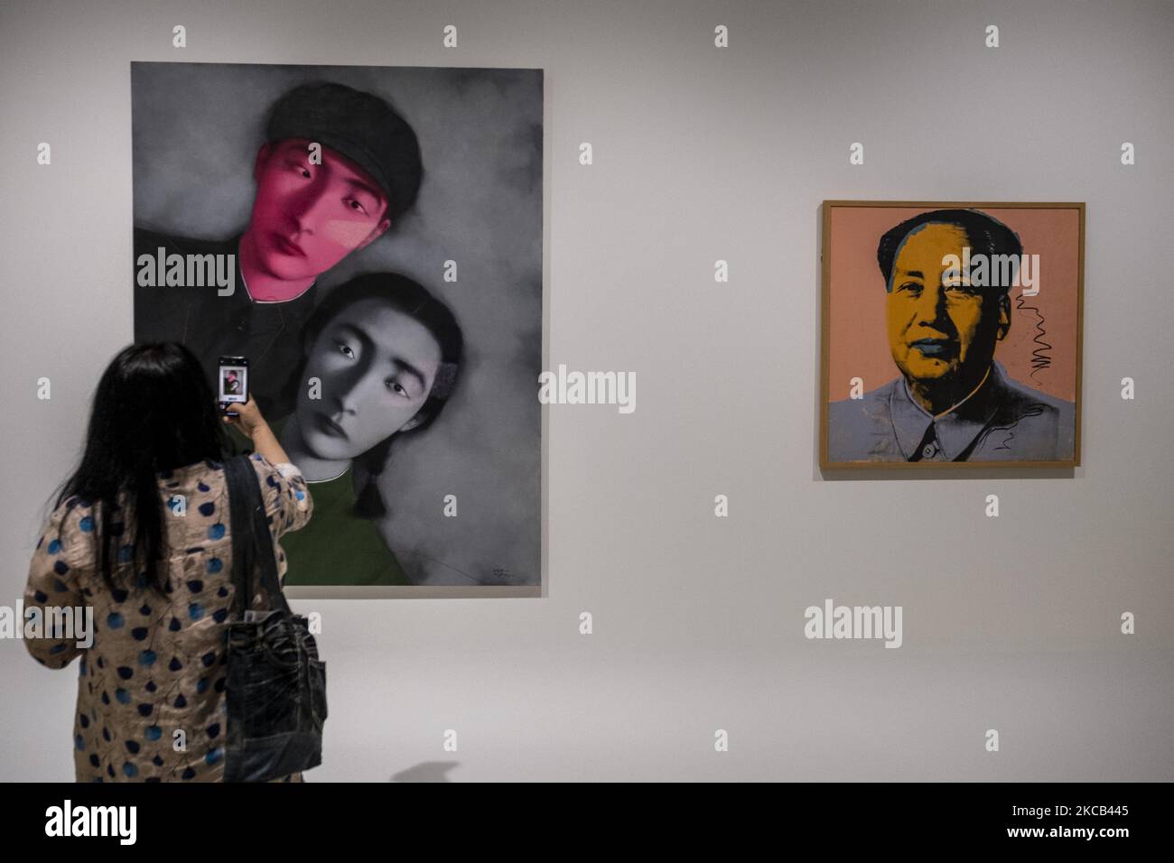 A Women fotografiert ein Gemälde von Zhang Xiaogang mit dem Namen ‘Big Family No. 1’ in der Kunstausstellung ‘Not a Fashion Store’ in Hongkong, Donnerstag, 18. März 2021. (Foto von Vernon Yuen/NurPhoto) Stockfoto