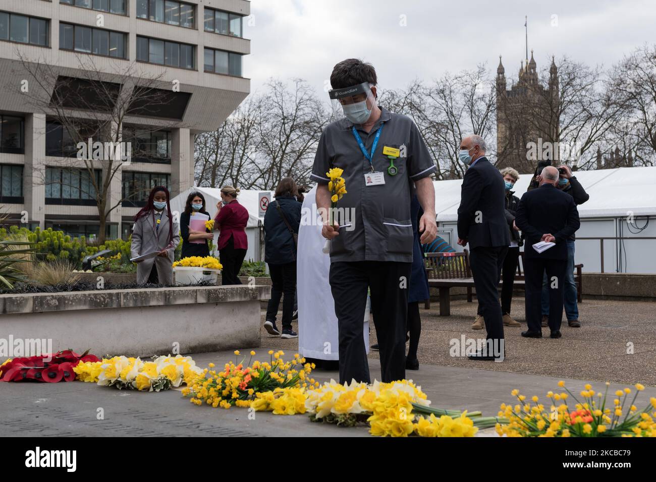 LONDON, GROSSBRITANNIEN – 23. MÄRZ 2021: Mitarbeiter des NHS legen Blumen vor dem St. Thomas's Hospital im Zentrum von London ab, um sich an diejenigen zu erinnern, die an dem Coronavirus gestorben sind, als Teil des National Day of Reflection, der ein Jahr seit der Ankündigung des britischen Premierministers Boris Johnson stattfand, dass das Land in die erste Aussperrung gehen würde, um die Ausbreitung von zu stoppen Covid-19, am 23. März 2021 in London, England. Seitdem hat das Vereinigte Königreich die schlimmste Todesrate von Covid-19 in Europa mit mehr als 126.000 Todesopfern erlitten und die Wirtschaft erlebte den größten Abschwung seit 300 Jahren. (Foto von Wiktor Szymanowicz/NurPhoto) Stockfoto