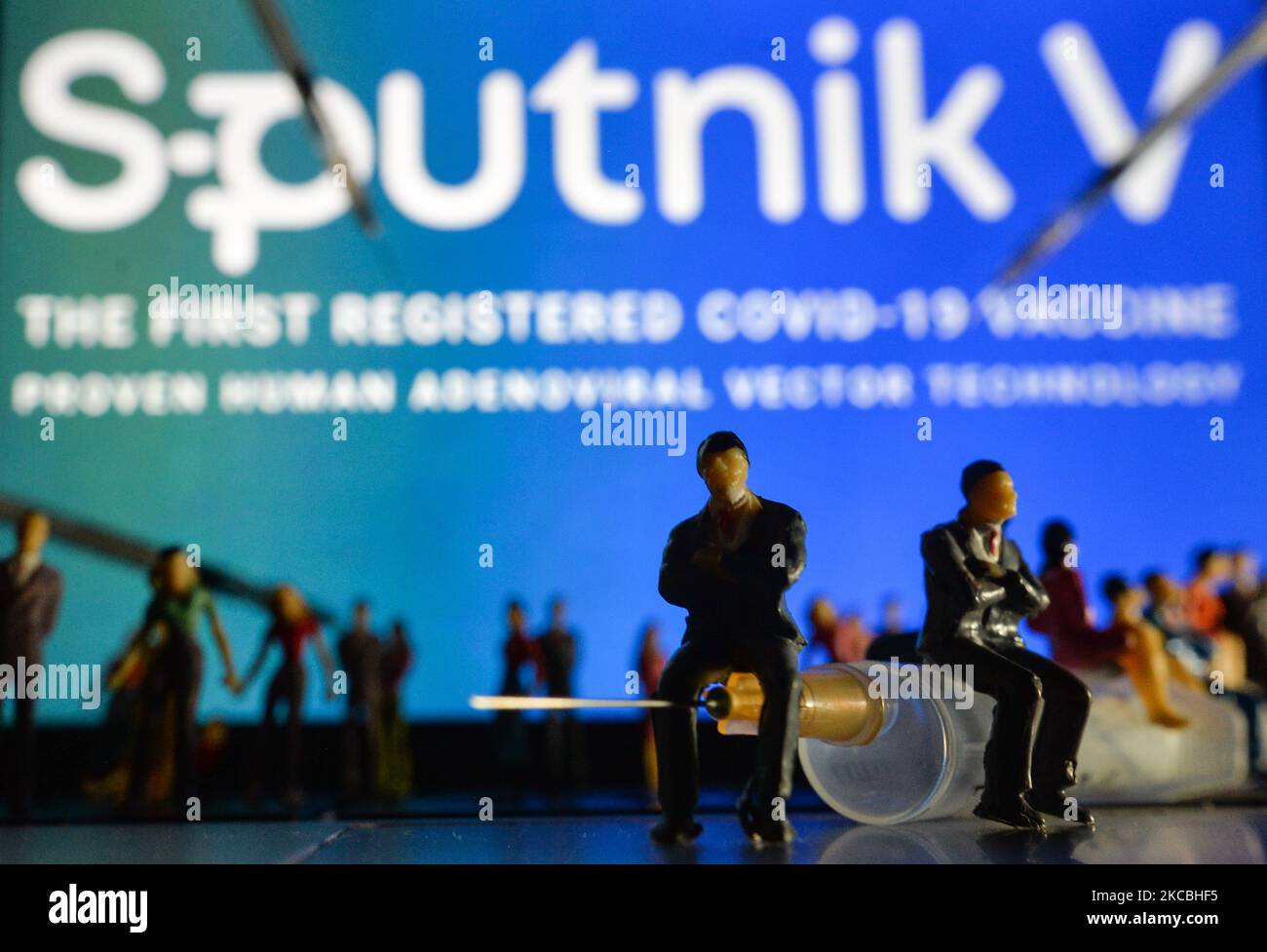 Medizinische Spritzen und kleine Figuren von Menschen sind vor dem Sputnik V-Logo auf einem Bildschirm zu sehen. Am Samstag, den 26. März 2021, in Dublin, Irland. (Foto von Artur Widak/NurPhoto) Stockfoto