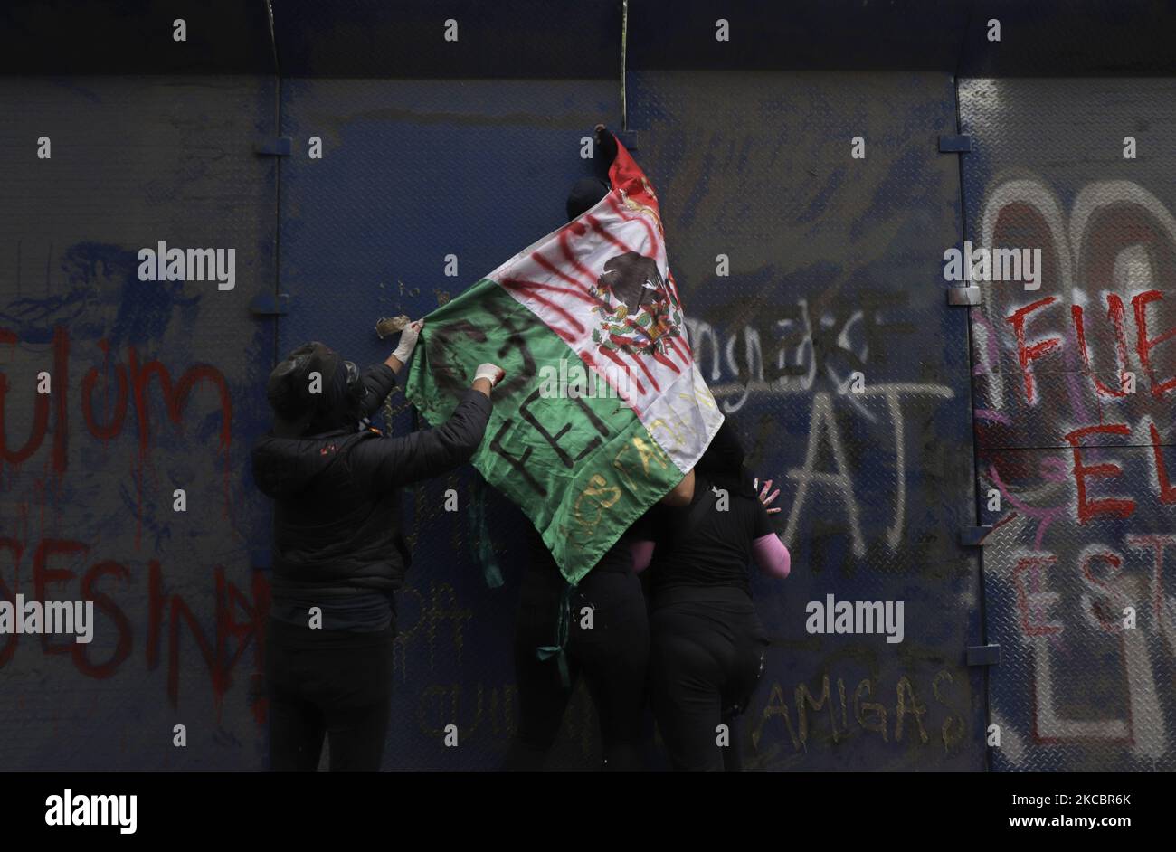 Mitglieder des feministischen schwarzen Blocks halten eine mexikanische Flagge und versuchen, Metallzäune vor der Vertretung von Quintana Roo in Mexiko-Stadt zu erklimmen, aus Protest gegen den Frauenmord von Victoria Salazar, einer salvadorianischen Migrantin, die von Polizisten aus Tulum unterjocht und ermordet wurde. (Foto von Gerardo Vieyra/NurPhoto) Stockfoto