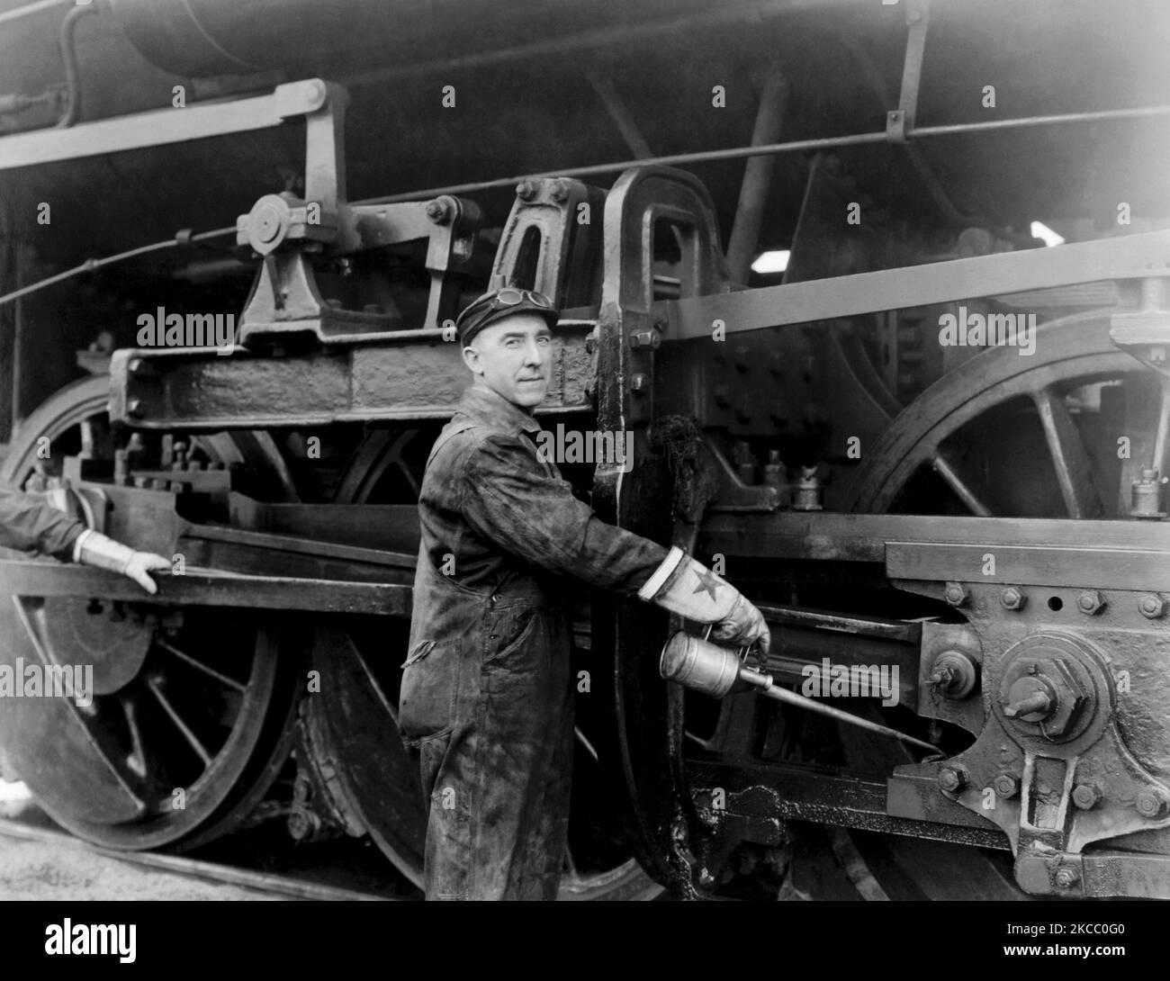 Ein Ingenieur, der aus der langen Nadelnase einer Ölkanüle die Räder einer Dampflokomotive einölt, um 1923. Stockfoto