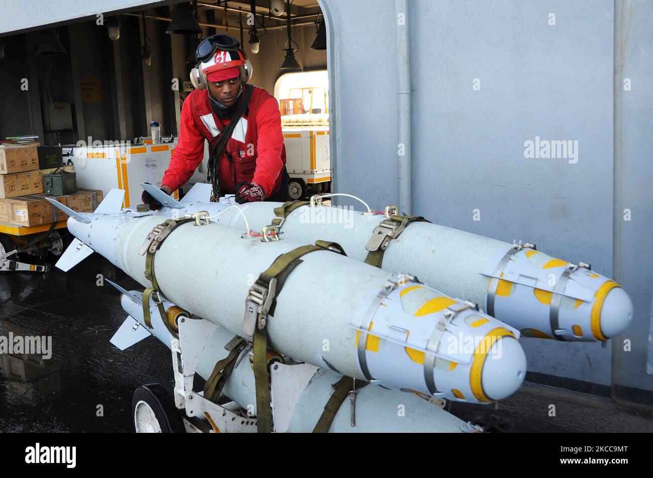 Aviation Ordnanceman bewegt geführte Bombeneinheiten an Bord der USS George H.W. Buchse. Stockfoto