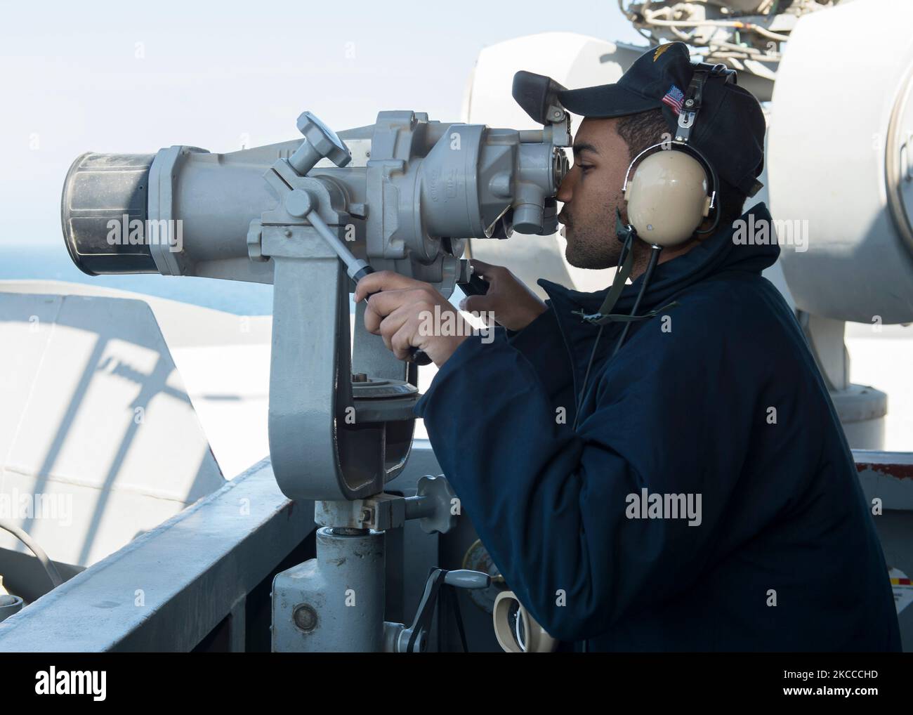 Boatswainâ €™s Mate Seaman verwendet High-Power-Fernglas, um den Horizont zu scannen. Stockfoto