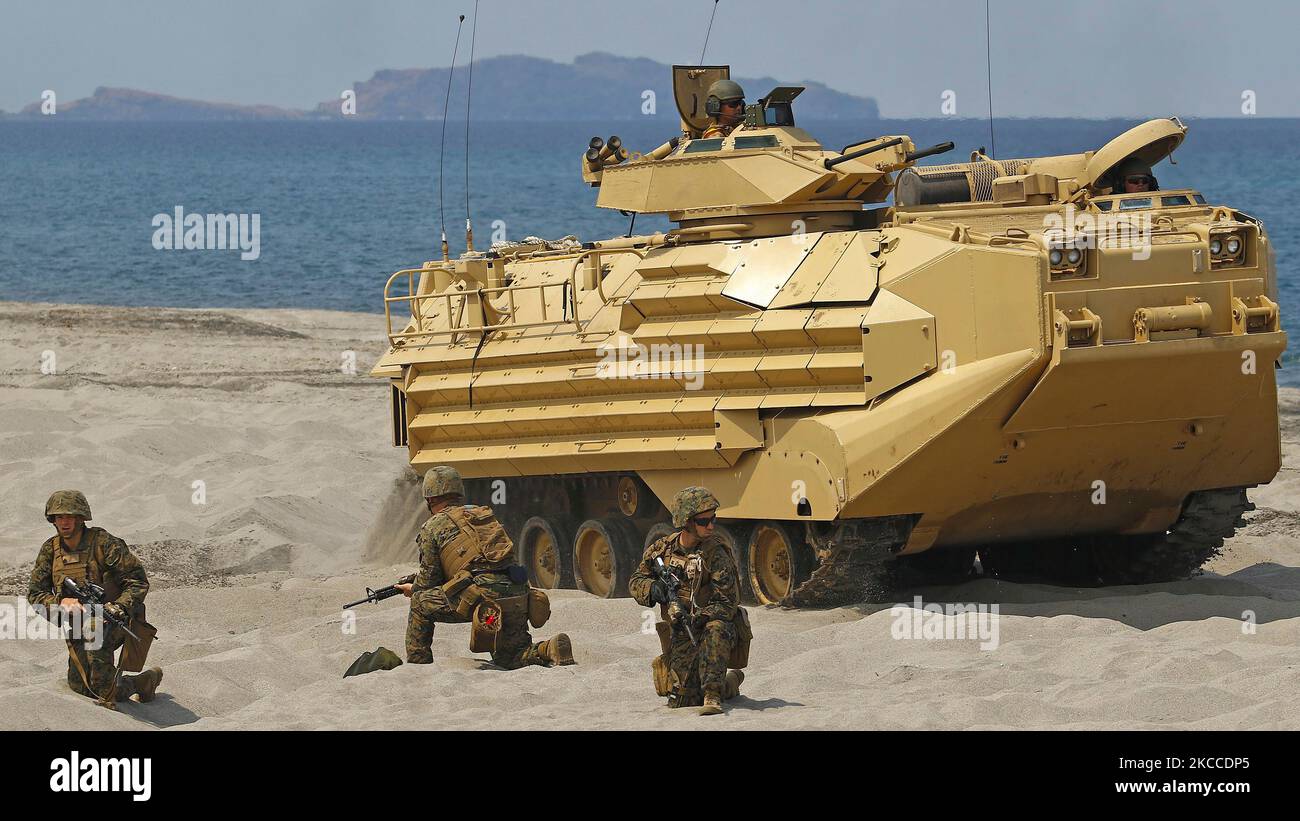 US-Marineinfanteristen stellen die Sicherheit nach, als ein amphibisches Angriffsfahrzeug die Position am Strand vorantreibt. Stockfoto