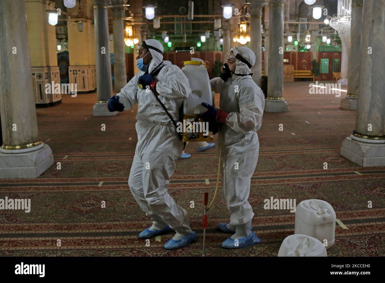 Arbeiter, die Gesichtsmasken tragen, sprühen Desinfektionsmittel, während sie sich während des gesegneten Monats Ramadan in der Sayeda Zeinab Moschee nach dem Ausbruch des Coronavirus (Covid-19) in Kairo, Ägypten, am 9. April 2021 auf das Gebet vorbereiten. (Foto von Fadel Dawod/NurPhoto) Stockfoto