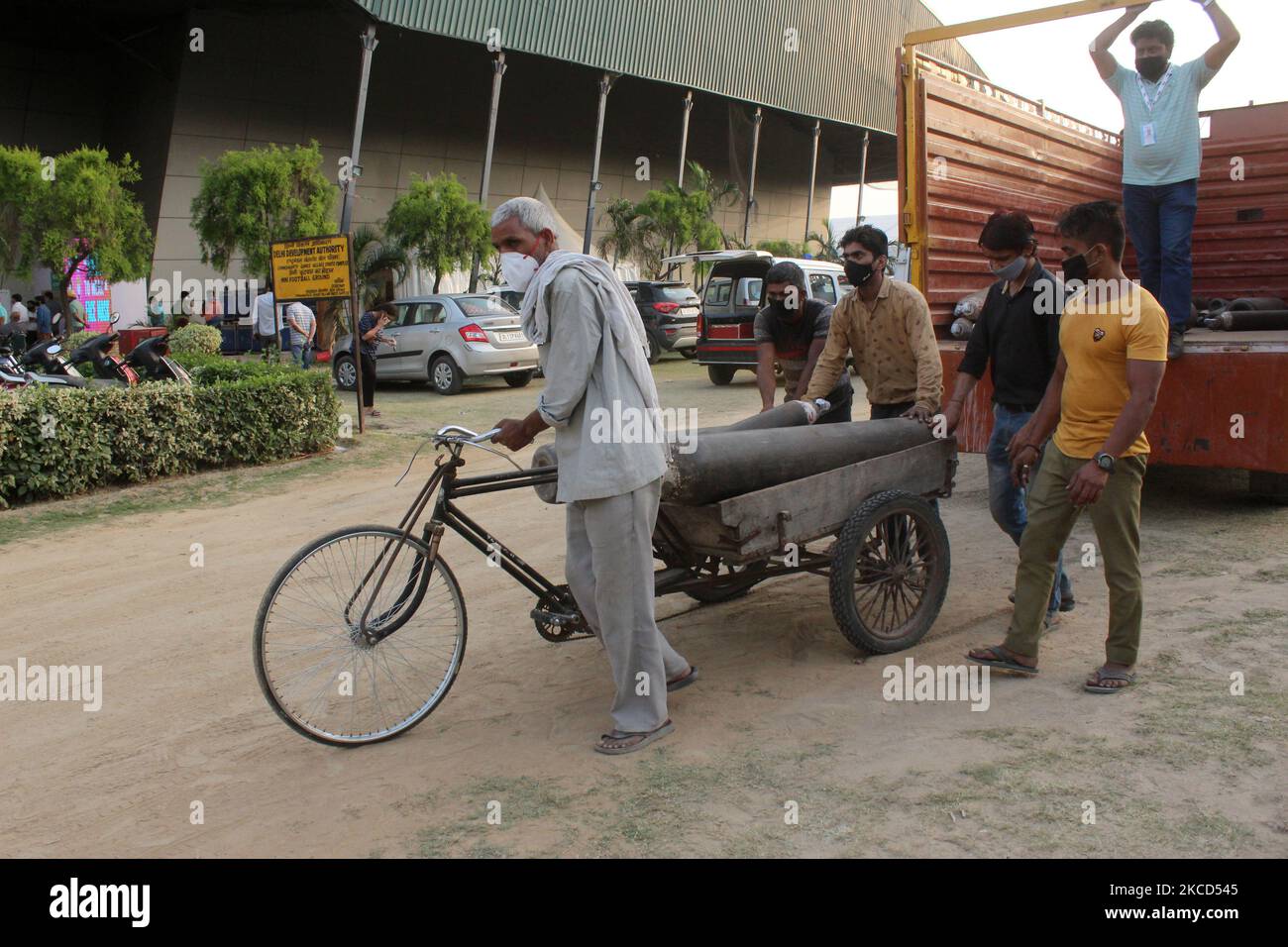 Angesichts der steigenden Zahl von Coronavirus-Fällen in Neu-Delhi am 21. April 2021 transportieren die Arbeiter nachgefüllte Sauerstoffflaschen von einem Lastwagen zu einer provisorischen Einrichtung, die in einem Sportkomplex errichtet wurde. Das Zentrum Verbot die Versorgung mit Sauerstoff für industrielle Zwecke mit Ausnahme von neun spezifizierten Branchen, da in mehreren Staaten aufgrund eines Anstiegs der COVID-19-Infektionen das lebenswichtige gut für die öffentliche Gesundheit fehlt. (Foto von Mayank Makhija/NurPhoto) Stockfoto