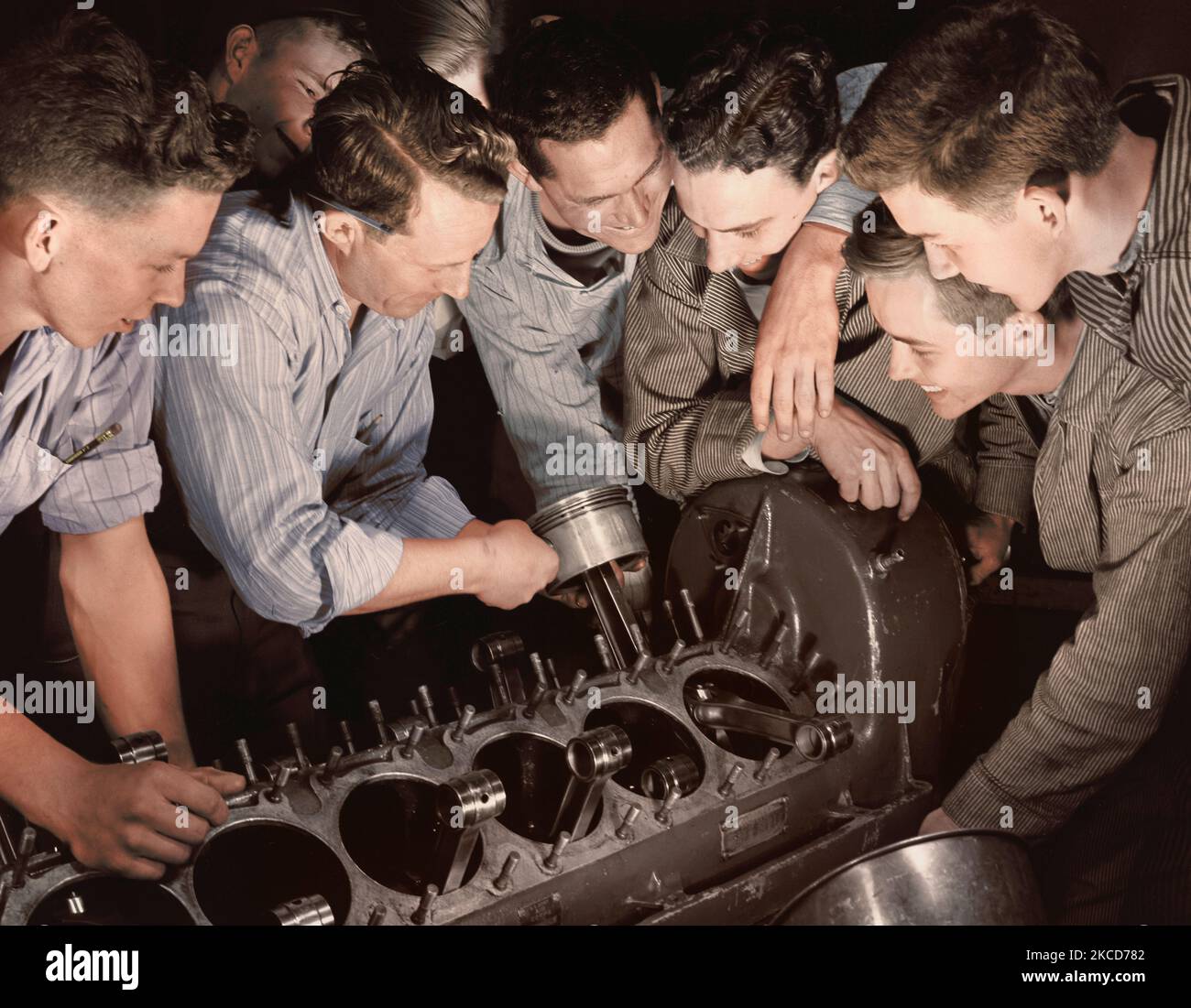 Lehrer zeigt einer Gruppe von Männern, wie einen Flugzeugmotor zusammenzubauen. Stockfoto