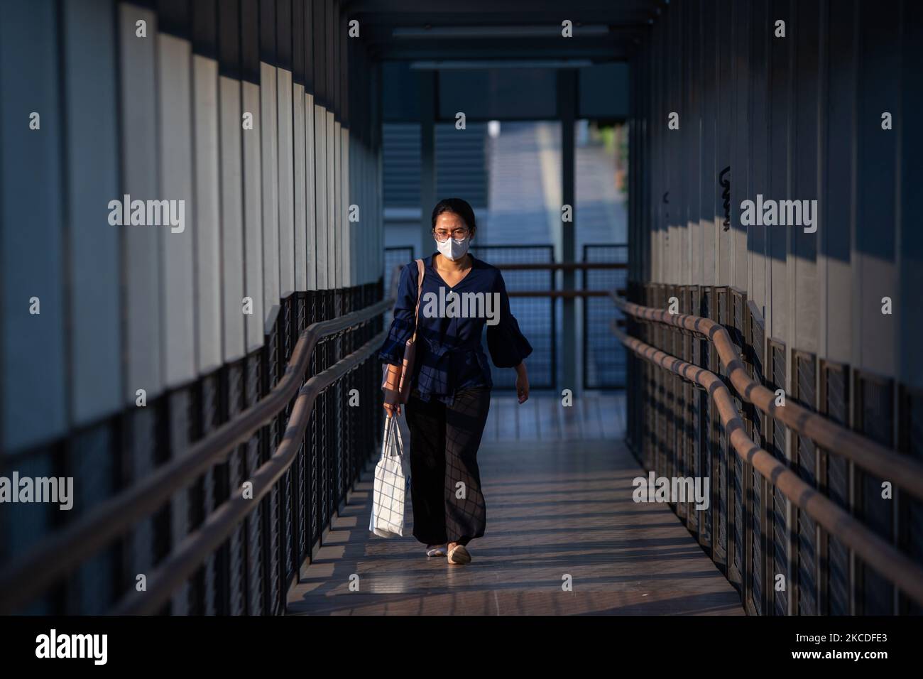 Eine Frau trägt Schutzmasken und geht am 26. April 2021 an der Fußgängerbrücke im Geschäftsviertel von Jakarta spazieren. Die Regierung der Provinz Jakarta hat die Öffentlichkeit aufgefordert, wachsam gegen die Übertragung von COVID-19 an den Arbeitsplätzen zu bleiben, da die Zahl der Beschäftigten, die dem Virus aus dem Büroverbund ausgesetzt waren, im April zugenommen hat. Die Zahl der aktiven Fälle aus dem Bürocluster erreichte am 12. Und 18. April 425 von 177 Arbeitsplätzen. Die meisten der gefundenen positiven Fälle waren von Arbeitsplätzen, die Impfungen erhalten haben. (Foto von Afriadi Hikmal/NurPhoto) Stockfoto