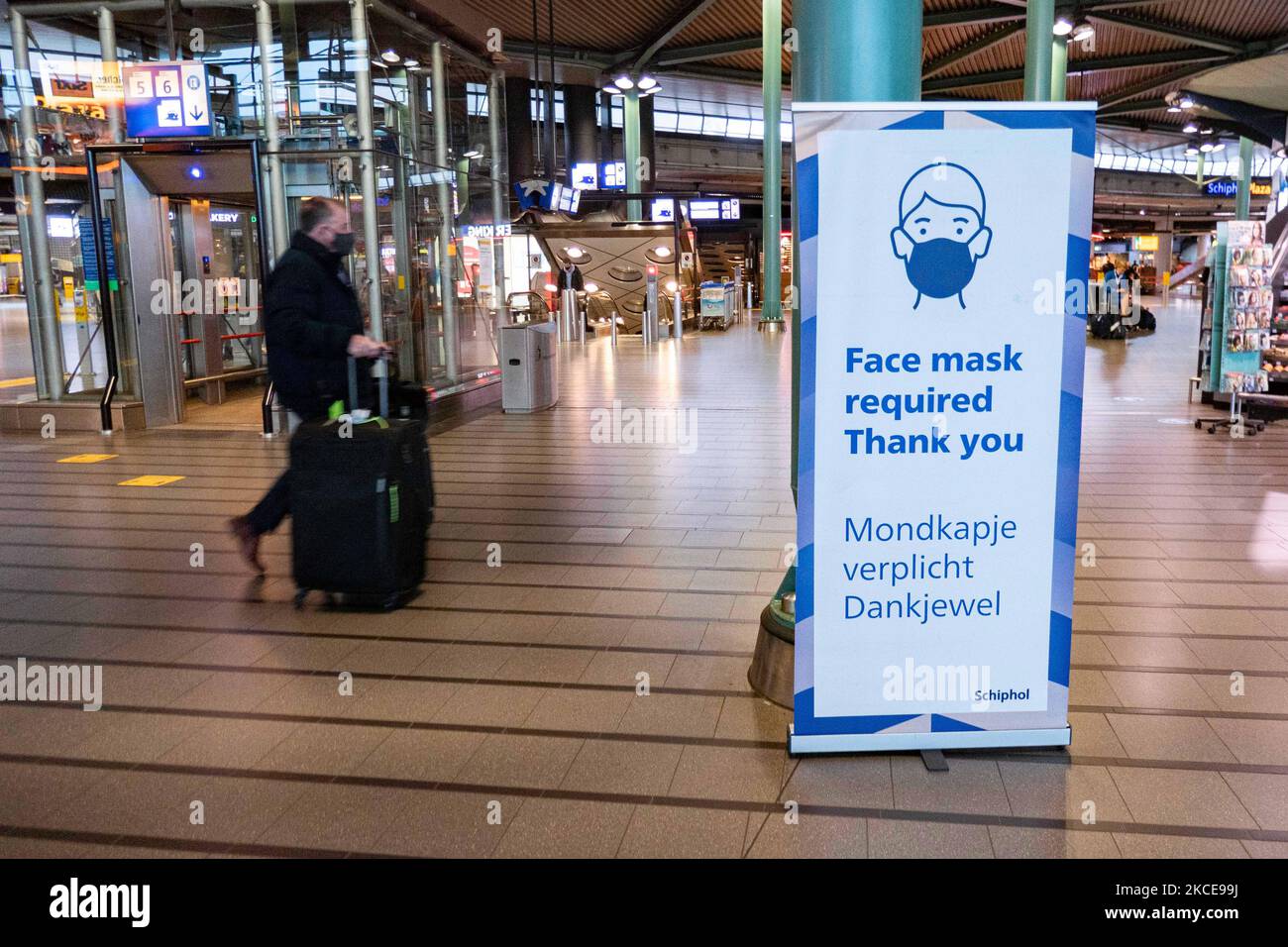Ein Banner mit der Aufschrift „Gesichtsmaske erforderlich Danke“ im Terminal des internationalen Flughafens Amsterdam Schiphol während der Pandemie Covid-19. Die Anzahl der Passagiere und die Crew tragen Schutzausrüstung wie die obligatorischen Gesichtsmasken und Handschuhe, um die Ausbreitung des Coronavirus zu vermeiden. Die Zahl der Passagiere im Weltflug sank aufgrund der Reisebeschränkungen, Sicherheitsmaßnahmen wie Sperren, Quarantäne, PCR und Schnelltests vor den Flügen, während der Ära der Coronavirus-Pandemie Covid-19, die die Luftfahrt schwer getroffen hatte Stockfoto