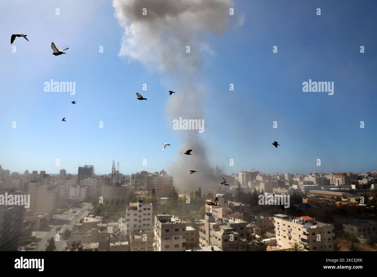 Eine dicke Rauchsäule steigt vom Jala-Turm auf, als er am 15. Mai 2021 bei einem israelischen Luftangriff in Gaza-Stadt, der von der palästinensischen Hamas-Bewegung kontrolliert wird, zerstört wird. - Israelische Luftangriffe schlugen den Gazastreifen ein, töteten 10 Mitglieder einer Großfamilie und zerstörten ein wichtiges Mediengebäude, während palästinensische Kämpfer im Gegenzug unter Gewalt im Westjordanland Raketen abfeuerten. Die israelische Luftwaffe zielte auf den 13-stöckigen Jala Tower, in dem das in Katar ansässige Al-Jazeera-Fernsehen und die Nachrichtenagentur Associated Press untergebracht sind. (Foto von Majdi Fathi/NurPhoto) Stockfoto