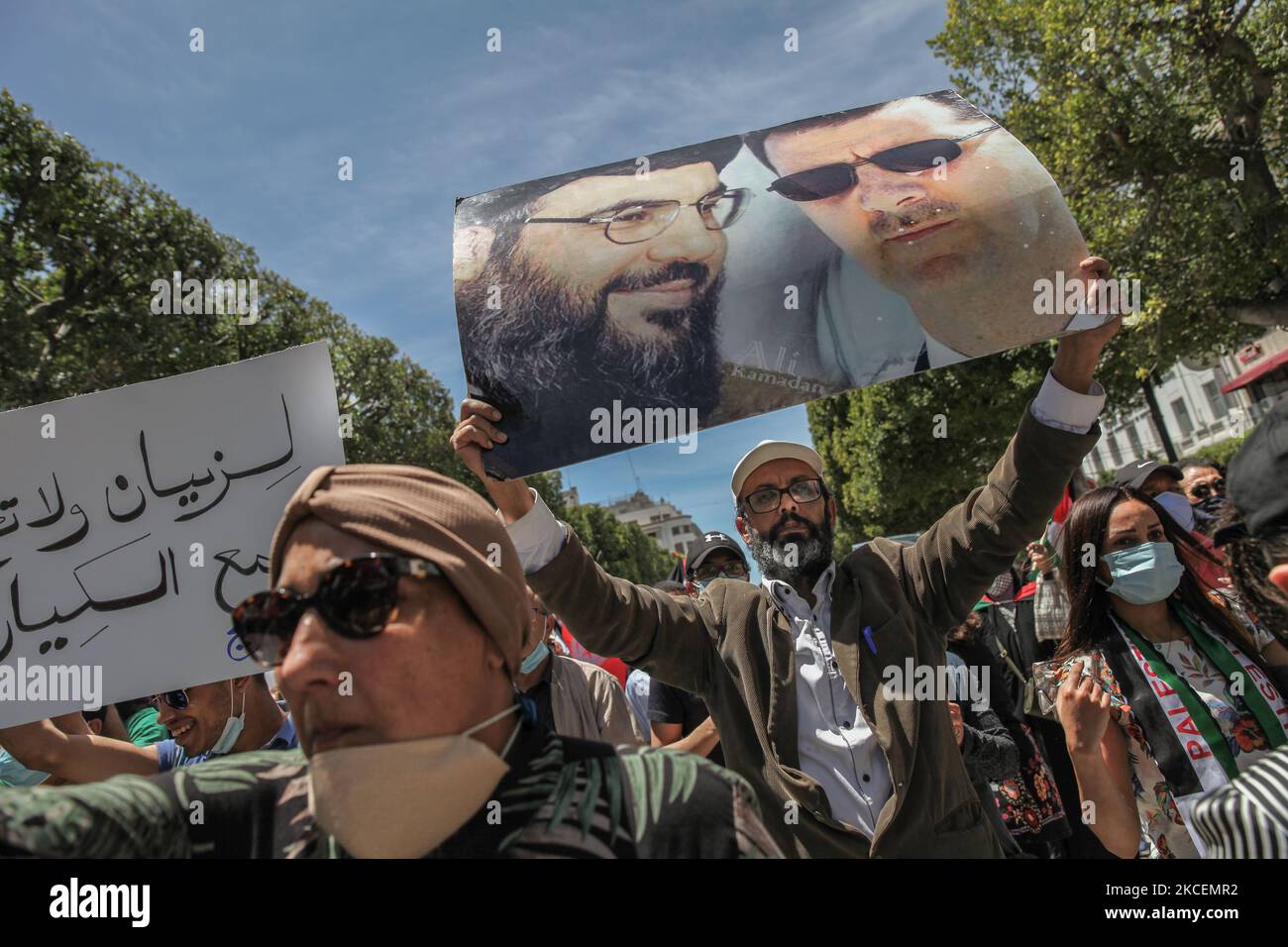 Ein Protestler hebt ein Plakat mit einem Fotoportrait des syrischen Präsidenten Bachar al-Assad und des Führers der Hisbollah Hassan Nasrallah während einer Demonstration, die Tausende tunesischer und palästinensischer Demonstranten auf der Avenue Habib Bourguiba in der tunesischen Hauptstadt Tunis am 15. Mai 2021 veranstalteten, Zur Unterstützung des palästinensischen Volkes und zum Protest gegen die israelischen Luftangriffe auf den Gazastreifen und gegen die israelischen Verletzungen in den besetzten Gebieten Palästinas, insbesondere in der palästinensischen Nachbarschaft in Ostjerusalem, Sheikh Jarrah. (Foto von Chedly Ben Ibrahim/NurPhoto) Stockfoto