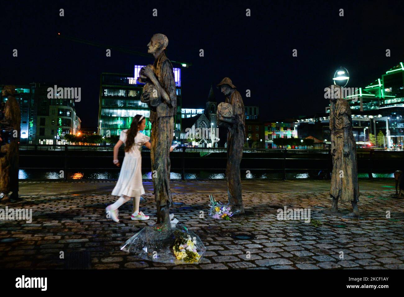 Sadhbh, ein kleines Mädchen, das der verstörten Frauenstatue am Mittwoch, dem 19. Mai, ihre Papiertaube anbietet, um ihr Leiden im Hungersnot Memorial in Dublin zu lindern, als Teil des neuen parallel Peace Project von Herstory, das am Welttag der kulturellen Vielfalt für Dialog und Entwicklung ins Leben gerufen wurde. Syrische, somalische, kenianische und libysche Aktivisten nahmen an einem Projekt in Dublin Teil, das die Geschichte von Frauen und Mädchen auf der irischen Insel erzählt, deren Leben von Kriegen und sozialen Konflikten heimgesucht wurde. Am Donnerstag, den 20. Mai 2021, in Dublin, Irland. (Foto von Artur Widak/NurPhoto) Stockfoto