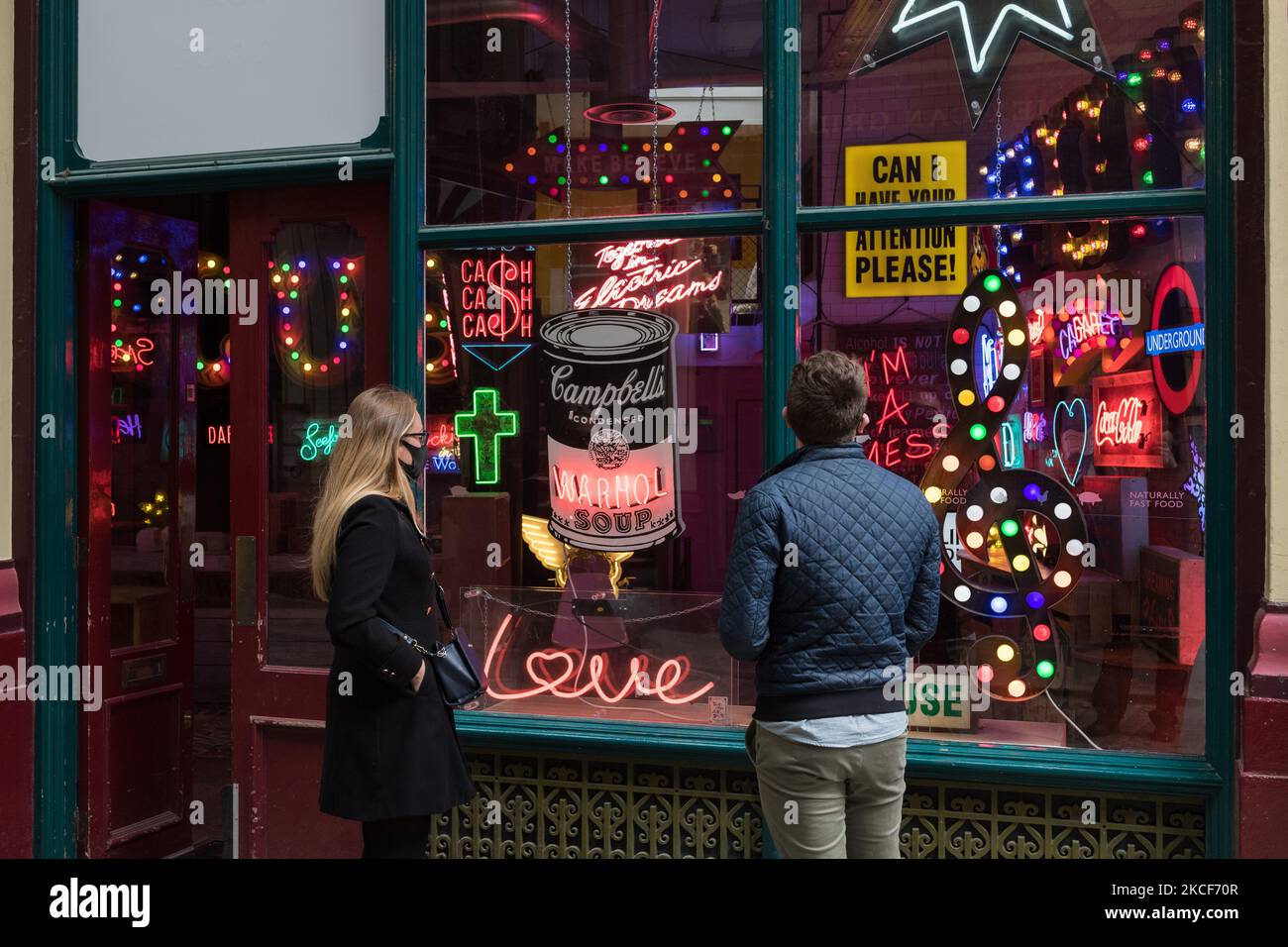 LONDON, GROSSBRITANNIEN - 25. MAI 2021: Besucher betrachten eine Installation mit Schildern und Neons aus Hollywood-Filmen, die vom verstorbenen Chris Bracey of Gods Own Junkyard während eines Fotoaufrufs für die Ausstellung „Electric City“ auf dem Leadenhall Market am 25. Mai 2021 in London, England, erstellt wurde. Gods Own Junkyard's and Leadenhall Market's Kollaboration „Electric City“ (26.. Mai – Samstag, 31.. Juli 2021) ist eine immersive Ausstellung von Neon- und Dreharbeiten, die für den Film gemacht wurden, einschließlich Signage-Highlights von Stanley Kubricks Eyes Wide Shut, Judge Dredd, Batman, Tomb Raider, Charlie und The Chocolate Factory und Th Stockfoto
