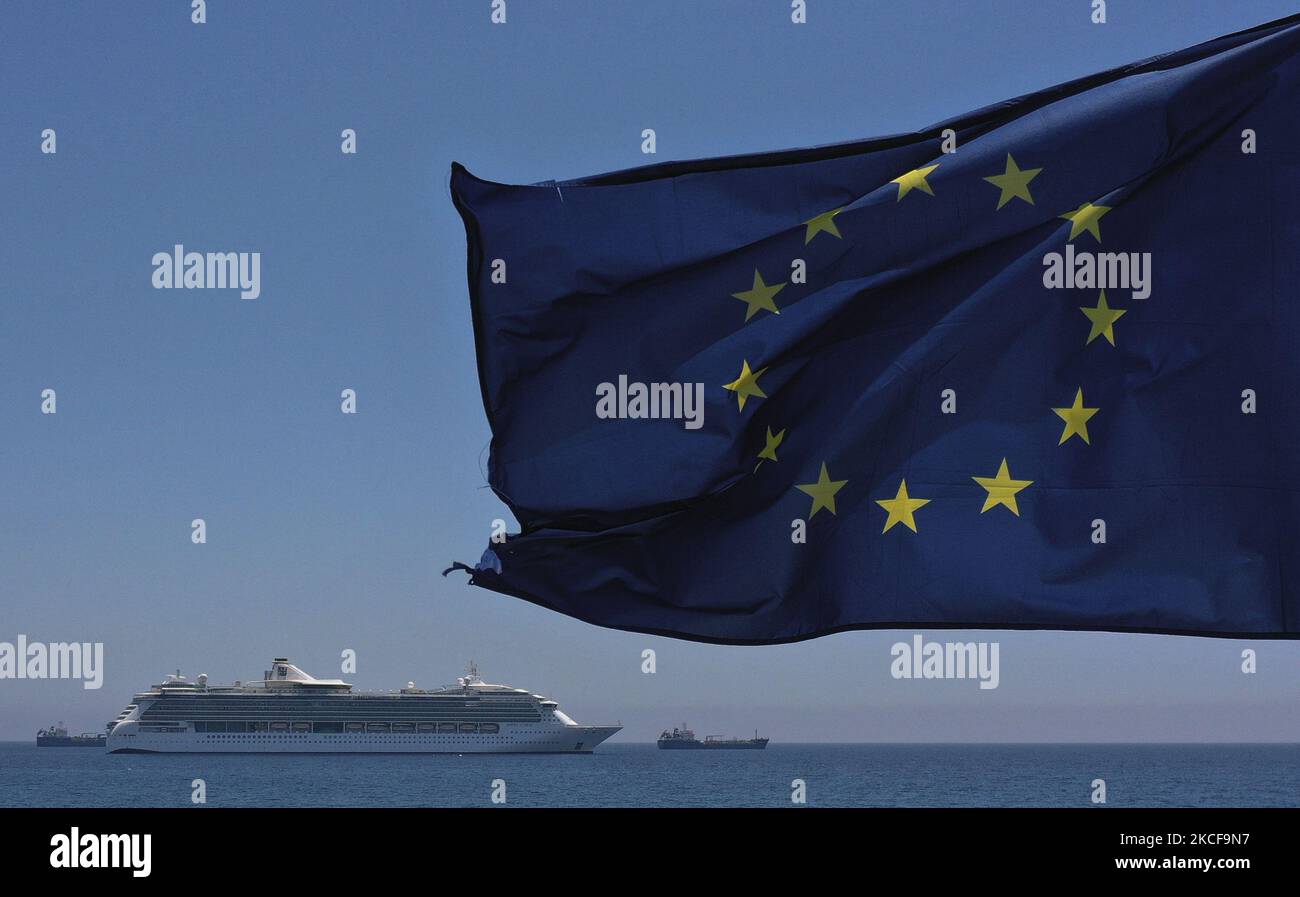 Ein Kreuzfahrtschiff vertäut hinter einer EU-Flagge, die im Wind auf einem Pier im Mittelmeer-Hafen von Limassol weht. Zypern, Donnerstag, 27. Mai 2021. Die Europäische Kommission hat der Republik Zypern 124 Millionen Euro übertragen. Dies ist die siebte Tranche im Rahmen des SURE-Programms, das von der Europäischen Union während der Coronavirus-Pandemie entwickelt wurde. Die Mittel, die Zypern aus der EU erhält, werden verwendet, um einen Teil der Gehälter der Arbeitnehmer jener Unternehmen zu bezahlen, die während der Sperrung geschlossen wurden. (Foto von Danil Shamkin/NurPhoto) Stockfoto