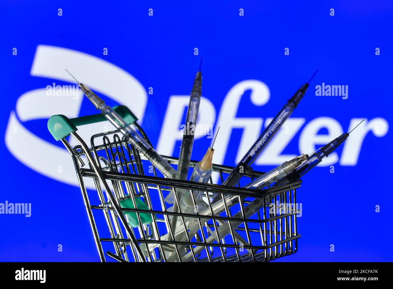 Medizinische Spritzen im Mini-Einkaufswagen sind vor dem Pfizer-Logo auf einem Bildschirm zu sehen. Am Freitag, den 28. Mai 2021, in Dublin, Irland. (Foto von Artur Widak/NurPhoto) Stockfoto