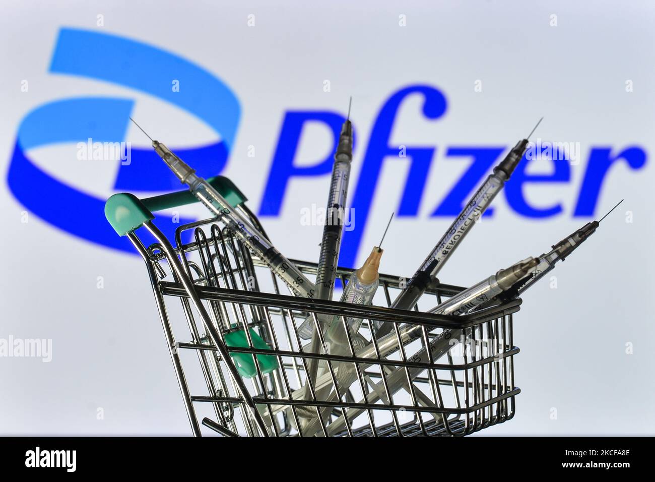 Medizinische Spritzen im Mini-Einkaufswagen sind vor dem Pfizer-Logo auf einem Bildschirm zu sehen. Am Freitag, den 28. Mai 2021, in Dublin, Irland. (Foto von Artur Widak/NurPhoto) Stockfoto