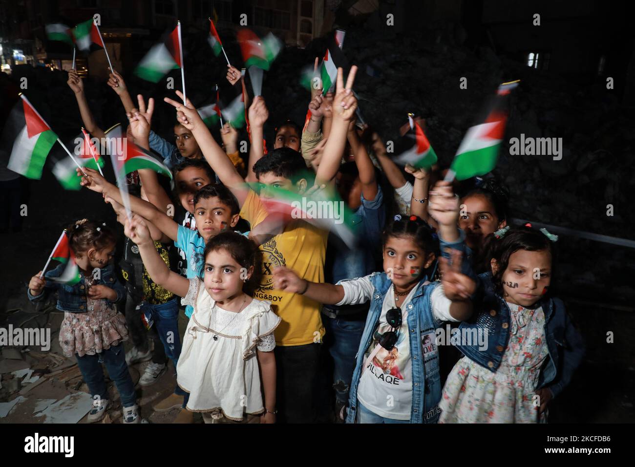 Palästinensische Kinder halten während einer Kundgebung in Gaza-Stadt am 30. Mai 2021 unter den Ruinen der Häuser, die durch israelische Angriffe zerstört wurden, die palästinensische Fahne fest. (Foto von Majdi Fathi/NurPhoto) Stockfoto