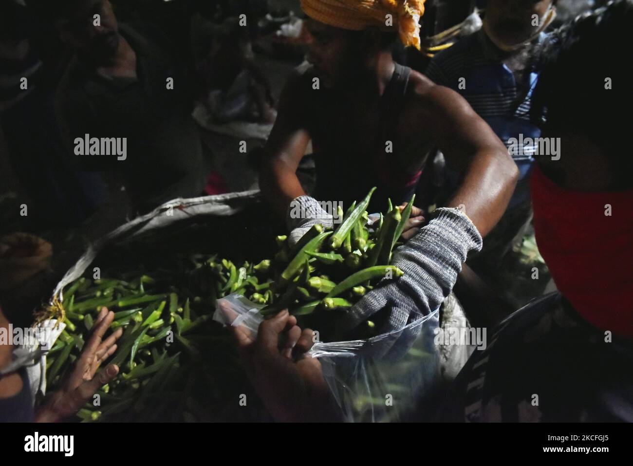 Ein Gemüseverkäufer trägt Handschuhe, während er auf einem Gemüsemarkt in Kalkutta, Indien, am 02. Juni 2021 ein Gemüse aus einem Sack sortiert. Indien bereitet derzeit ein Konjunkturpaket für Sektoren vor, die am stärksten von einer tödlichen Coronavirus-Welle betroffen sind, und zielt darauf ab, eine Wirtschaft zu unterstützen, die mit einer Reihe örtlich begrenzter Sperrungen zu kämpfen hat, sagten Leute, die mit der Angelegenheit vertraut sind. Laut einem indischen Medienbericht arbeitet das Finanzministerium an Vorschlägen zur Stärkung der Tourismus-, Luftfahrt- und Gastgewerbe sowie kleiner und mittlerer Unternehmen. (Foto von Indranil Aditya/NurPhoto) Stockfoto