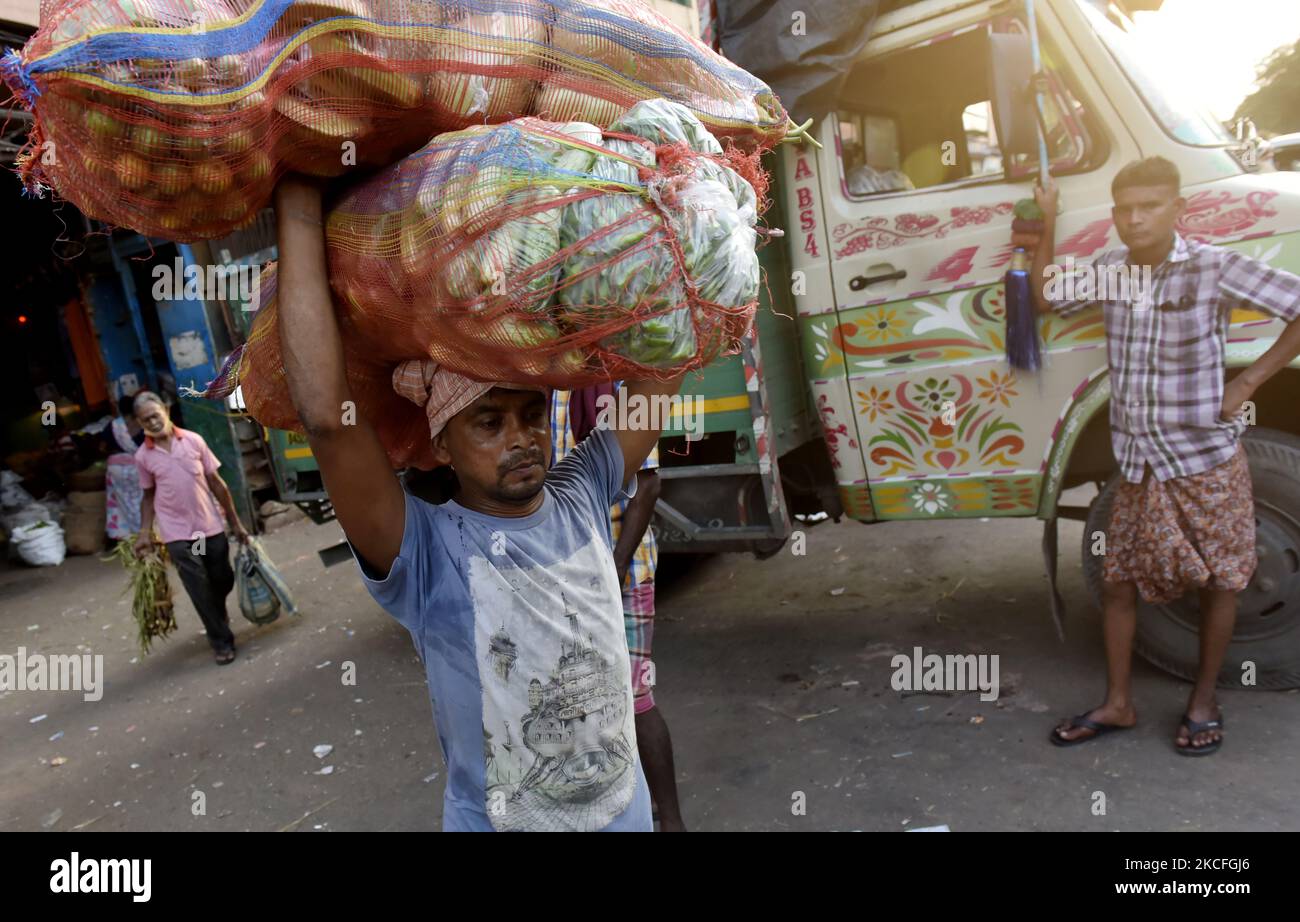 Ein Arbeitsmigranten trägt Gemüsesack auf dem Kopf von einem Gemüsemarkt in Kalkutta, Indien, 02. Juni 2021. Indien bereitet derzeit ein Konjunkturpaket für Sektoren vor, die am stärksten von einer tödlichen Coronavirus-Welle betroffen sind, und zielt darauf ab, eine Wirtschaft zu unterstützen, die mit einer Reihe örtlich begrenzter Sperrungen zu kämpfen hat, sagten Leute, die mit der Angelegenheit vertraut sind. Laut einem indischen Medienbericht arbeitet das Finanzministerium an Vorschlägen zur Stärkung der Tourismus-, Luftfahrt- und Gastgewerbe sowie kleiner und mittlerer Unternehmen. (Foto von Indranil Aditya/NurPhoto) Stockfoto