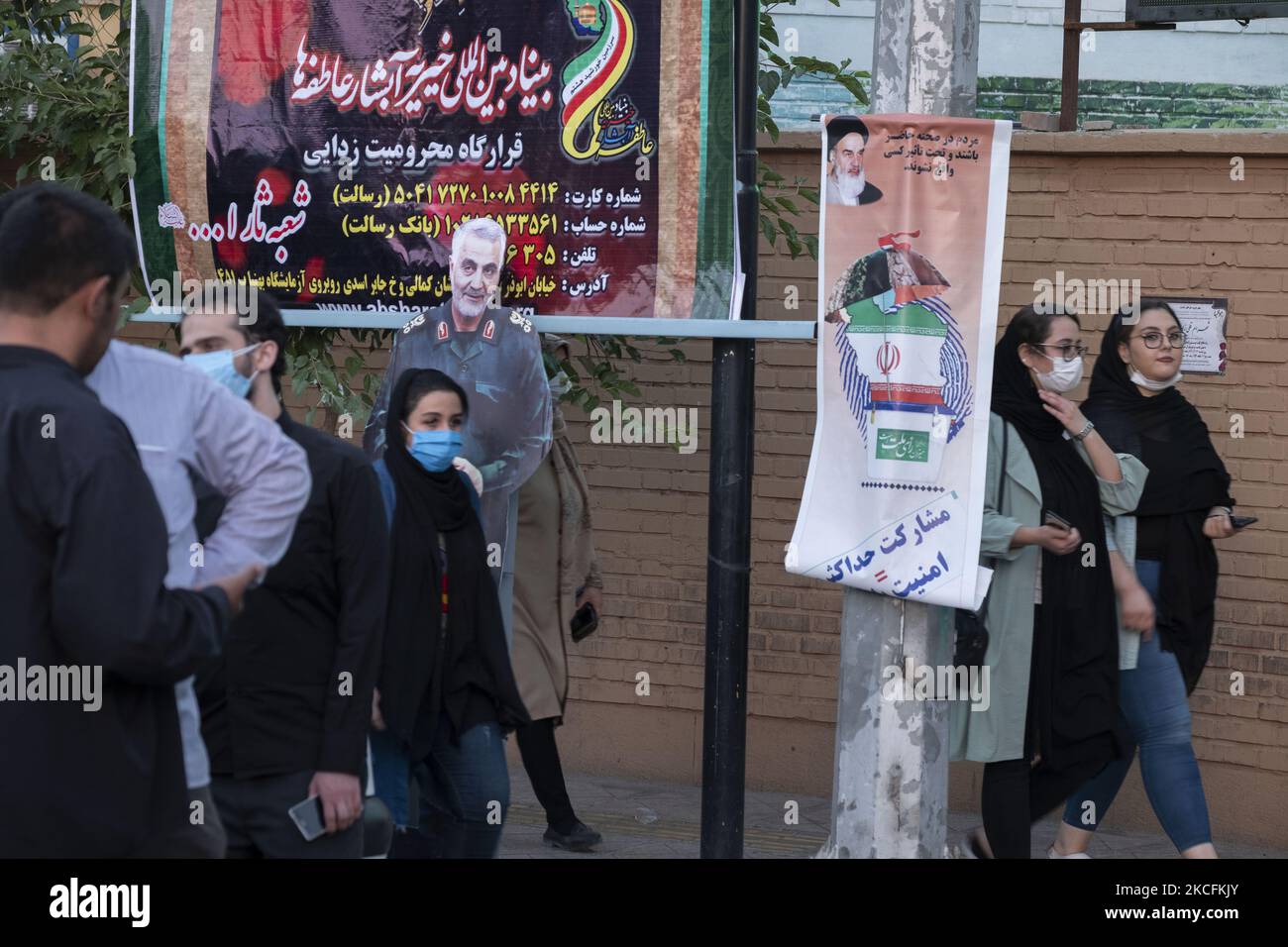 Iranische Frauen kommen an einem Wahlplakat und einem Bildnis des ehemaligen iranischen Korps der Islamischen Revolutionsgarde (IRGC) Quds Force General Qasem Soleimani vorbei, der während der Tage der Präsidentschaftswahlen am 4. Juni 2021 bei einem amerikanischen Drohnenangriff auf dem Flughafen Bagdad im Süden Teherans getötet wurde. (Foto von Morteza Nikoubazl/NurPhoto) Stockfoto