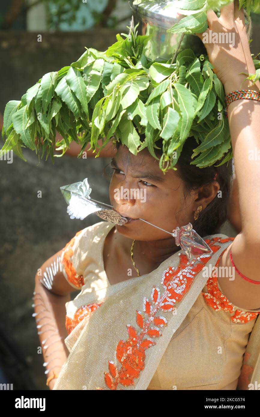 Tamilische Hindu-Frau mit einem Gesichtsspieß und Nadeln im Arm, während sie während des Nallur Ther Festivals (Nallur Chariot Festival) beim Nallur Kandaswamy Kovil (Nallur Tempel) in Jaffna, Sri Lanka, einen Topf auf ihrem Kopf trägt, der mit Milch und Honig gefüllt und mit Margosa-Blättern bedeckt ist. Hunderttausende tamilische Hindu-Anhänger aus der ganzen Welt nahmen an diesem Fest Teil. (Foto von Creative Touch Imaging Ltd./NurPhoto) Stockfoto