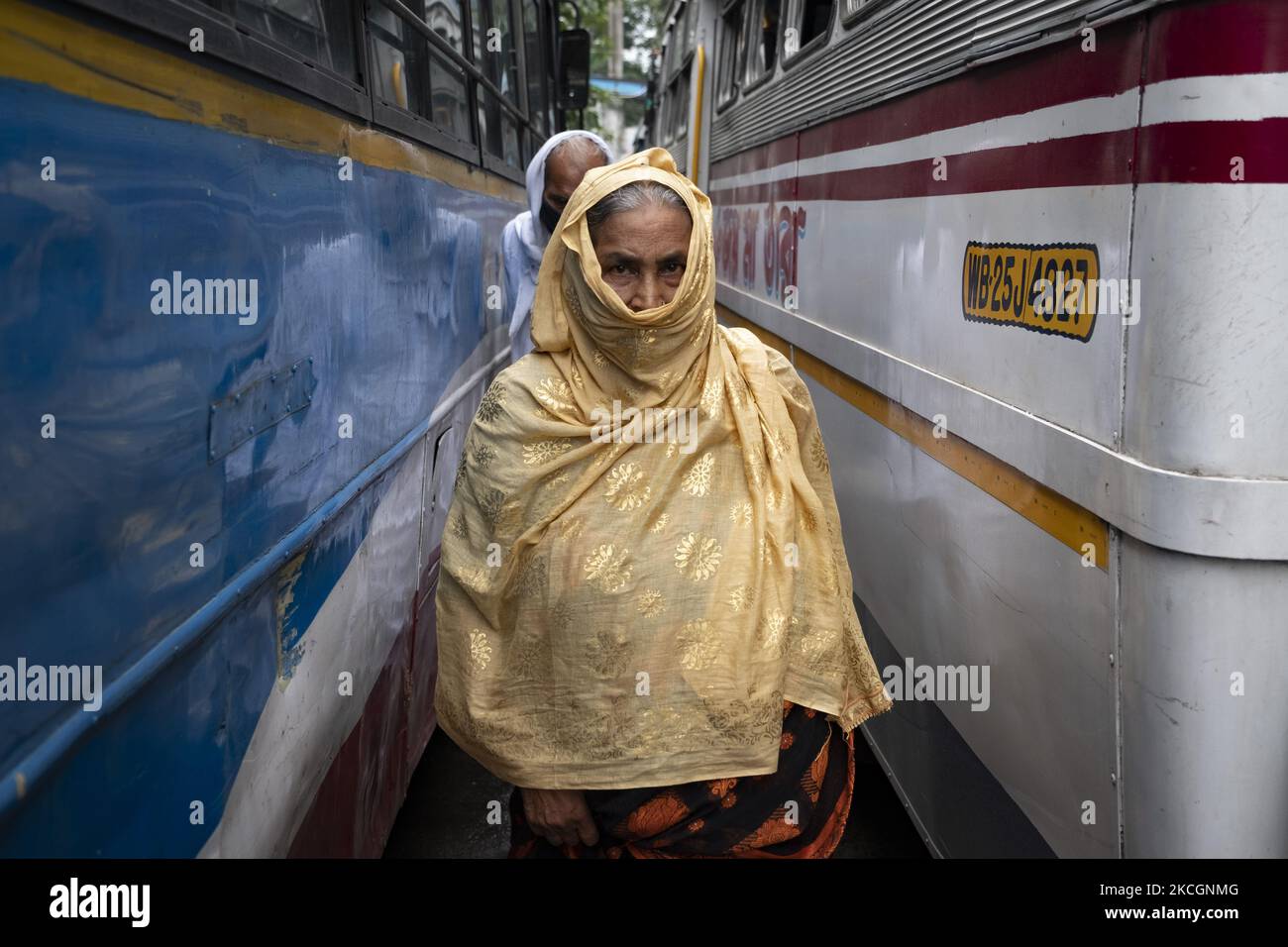 Eine alte Frau, die keine Sicherheitsmaske trug, bedeckte ihr Gesicht mit einem Tuch und überquerte am 1. Juli 2021 die Fahrspur einer Busstation in Kalkutta, Indien. West Bengalen Govt hat bestimmte Beschränkungen für die Sperre in Kraft gesetzt, die vom 1.. juli bis zum 15.. juli wirksam ist. Busse, Autos und toto-Dienste wurden mit einer Kapazität von 50 % wieder aufgenommen. Salon, Salon und Fitnessstudio können mit 50% Kunden eröffnet werden. Der lokale Zug und die U-Bahn werden laut dem indischen Medienbericht nicht in Betrieb sein. Obwohl die Busverbindungen nicht regelmäßig waren, da die Busverbände protestierten, den Bustarif zu steigen, und appellierten für eine Zwangsimpfung für alle Stockfoto