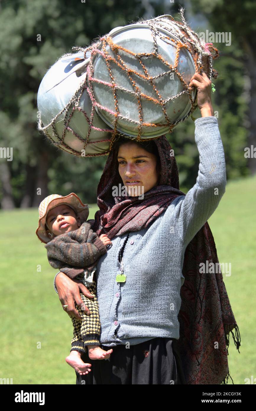 Die nomadische Bakharwalli-Frau trägt ein großes Paket von Töpfen und Pfannen auf ihrem Kopf und ihr Kind in ihren Armen, während sie sich auf ihren Umzug nach Pahalgam, Kaschmir, Indien, vorbereitet. (Foto von Creative Touch Imaging Ltd./NurPhoto) Stockfoto