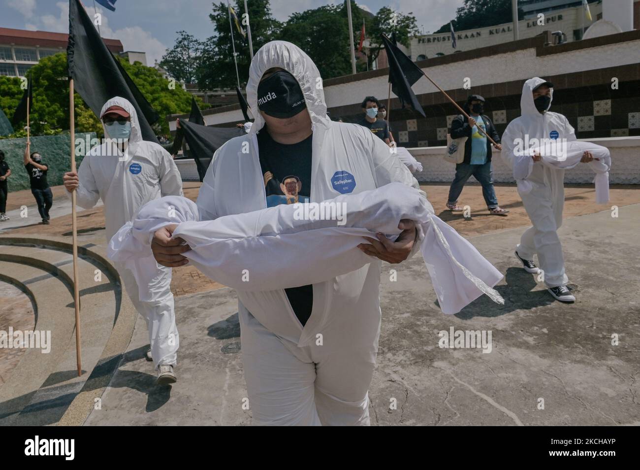 Demonstranten, die eine persönliche Schutzausrüstung tragen und eine Scheinleiche bei einem Protest unter schwarzer Flagge am 17. Juli 2021 in Kuala Lumpur, Malaysia tragen. Der #BlackFlag Protestorganisator, der die malaysische Regierung nach dem Anstieg der positiven Fälle von Covid-19 als gescheiterte Regierung kritisierte, 13.215 Fälle am 15. Juli 2021, in denen der Rücktritt des Premierministers Muhyiddin Yassin gefordert wurde, eine vollständige Parlamentssitzung und ein automatisches Moratorium für alle Menschen (Foto von Zahim Mohd/NurPhoto) Stockfoto