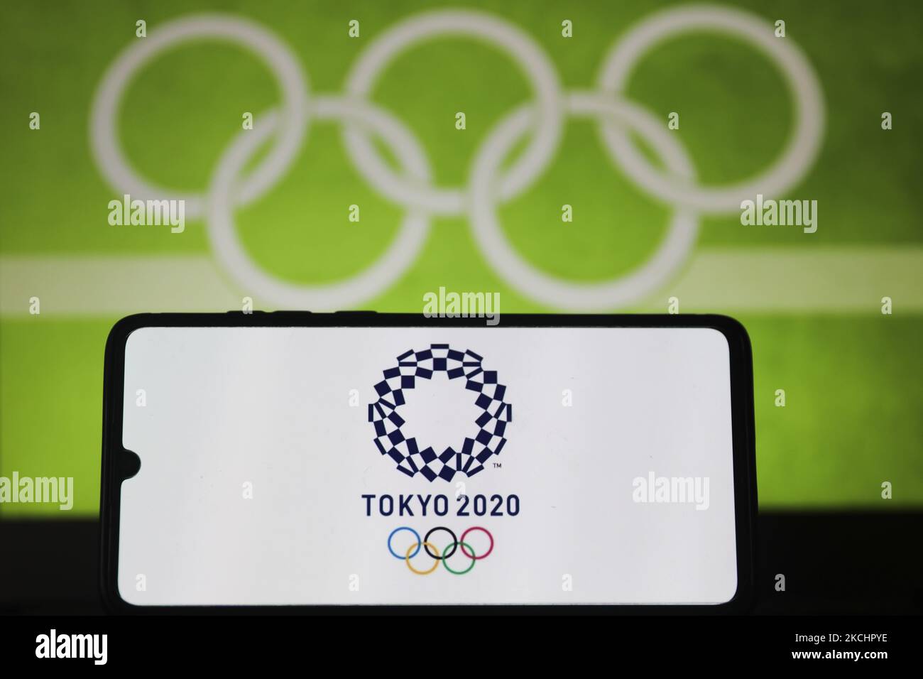 Das Logo der Olympischen Spiele 2020 in Tokio wird auf einem Handybildschirm angezeigt, der mit dem Symbol für die Olympischen Ringe auf dem Hintergrund fotografiert wurde, um ein Foto zu illustrieren. Leszczewek, Polen am 26. Juli 2021. (Foto von Beata Zawrzel/NurPhoto) Stockfoto