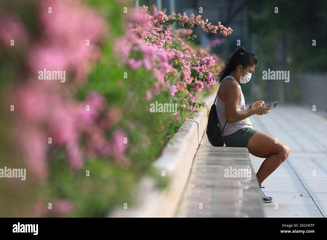 Eine Frau mit Schutzmaske überprüft am 29. Juli 2021 in Singapur ihr Mobiltelefon. (Foto von Suhaimi Abdullah/NurPhoto) Stockfoto