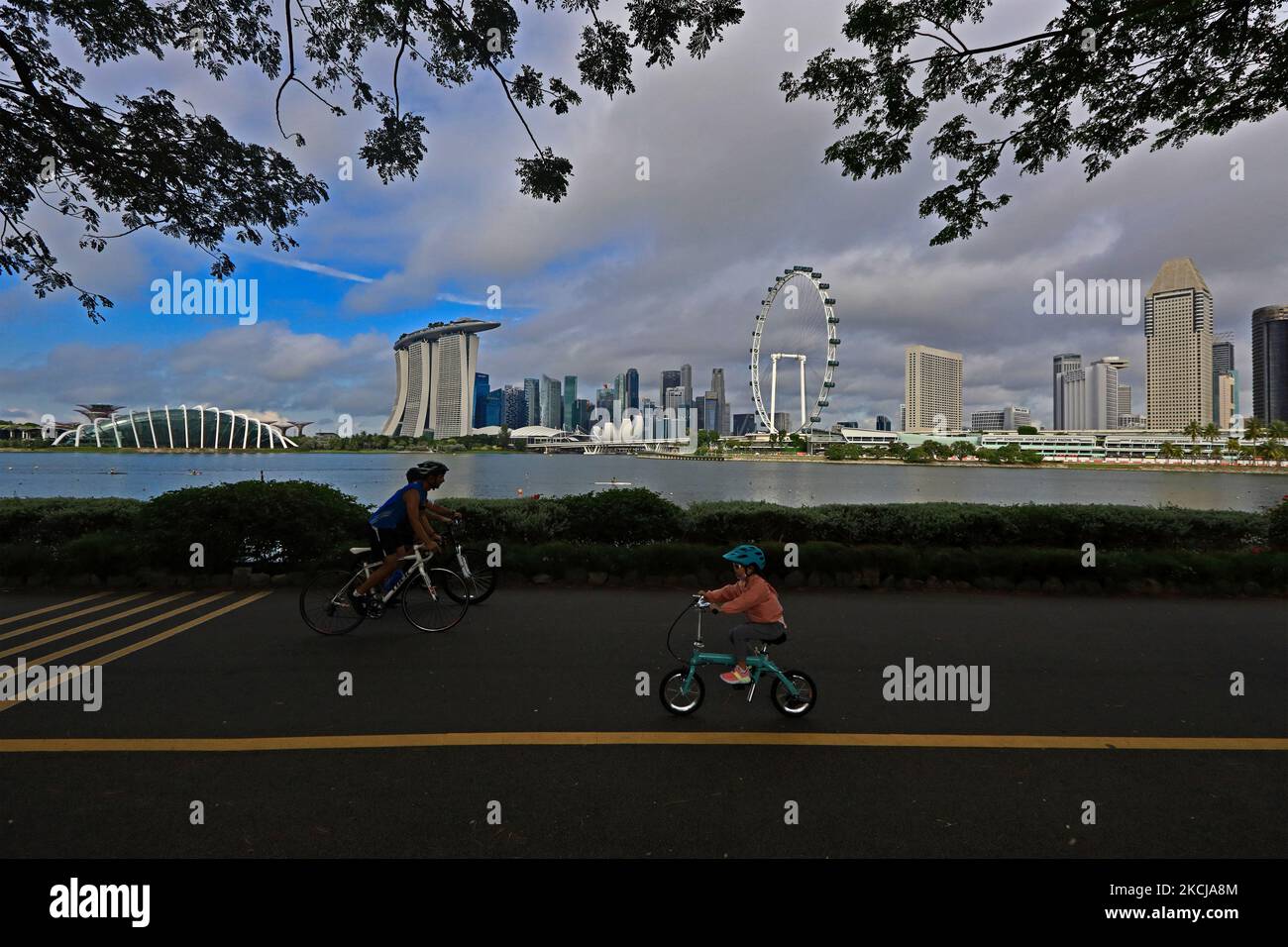 Am 7. August 2021 in Singapur radeln die Menschen entlang eines Parkanschlusses mit der Skyline der Stadt, die im Hintergrund bei Gardens by the Bay zu sehen ist. (Foto von Suhaimi Abdullah/NurPhoto) Stockfoto