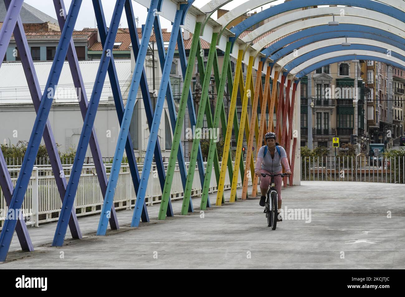 Eine junge Frau auf dem Fahrrad überquert die San Sebastian Brücke, die 2006 von dem Künstler Ramón Rodriguez restauriert wurde, und ist damit eine der Ikonen von Aviles und der wichtigste Fußgängerzugang zum Niemeyer Center. AVILES 08-17-2021 (Foto von Joaquin Gomez Sastre/NurPhoto) Stockfoto