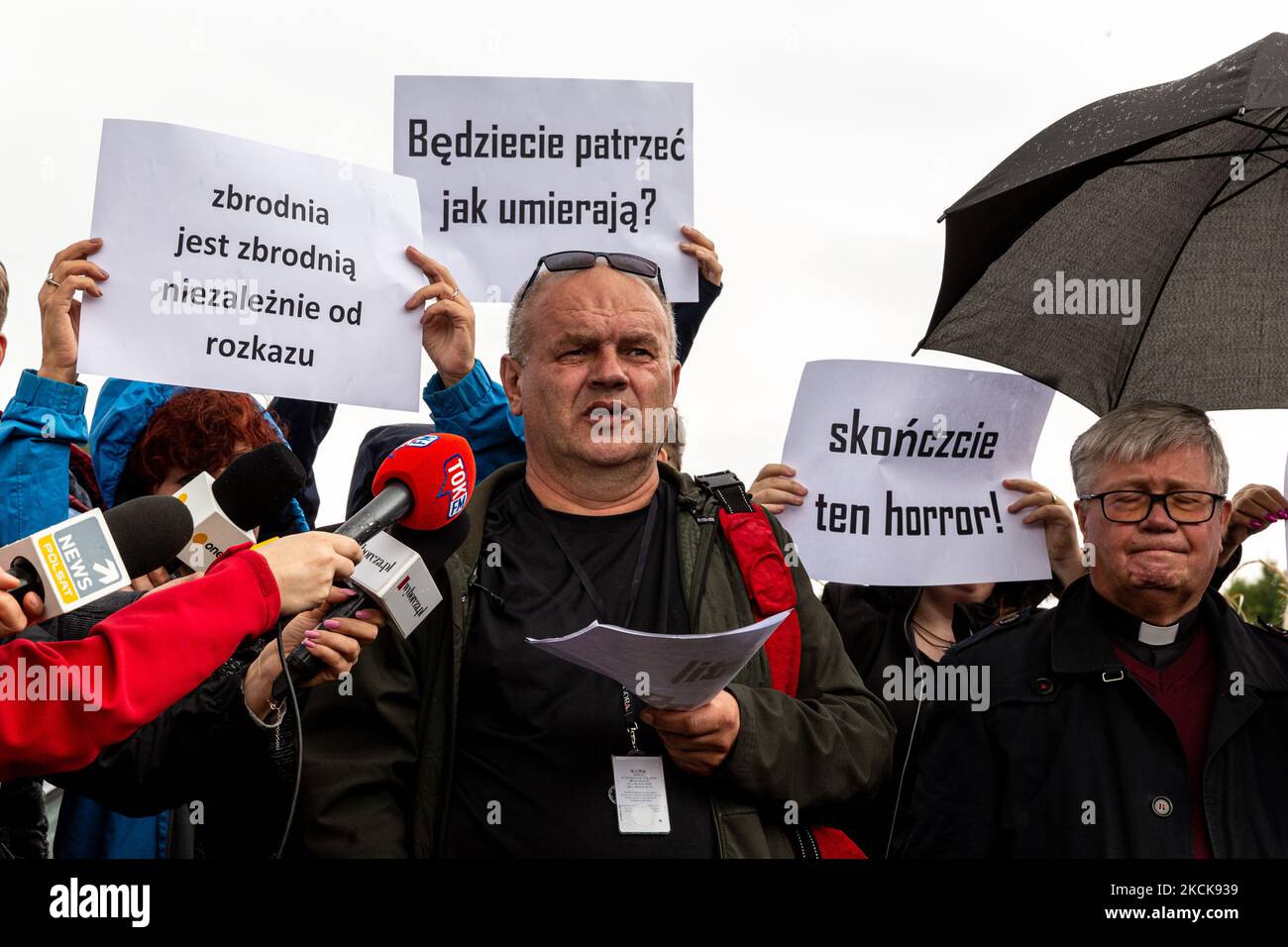 Aktivisten protestieren, während Soldaten der polnischen Armee eine Gruppe von Einwanderern aus Afghanistan an der weißrussischen Grenze umkreisen und ihre Einreise in das Land in Usnarz Gorny, Polen, am 27. August 2021 verhindern. Die Armee und die Polizei hielten die Migranten an der Grenze an und verhinderten, dass sie nach Polen einmarschieren konnten, die Armee verweigerte auch den Zugang zu Asylverfahren, medizinischer Hilfe und Lebensmitteln. Journalisten und Wohltätigkeitsarbeiter werden etwa 300 Meter entfernt gehalten. Die Aktionen der polnischen Regierung wurden weithin kritisiert. Die polnische Regierung beschloss auch, einen Zaun zu bauen, um dem Zustrom von Wanderern ein Ende zu setzen Stockfoto