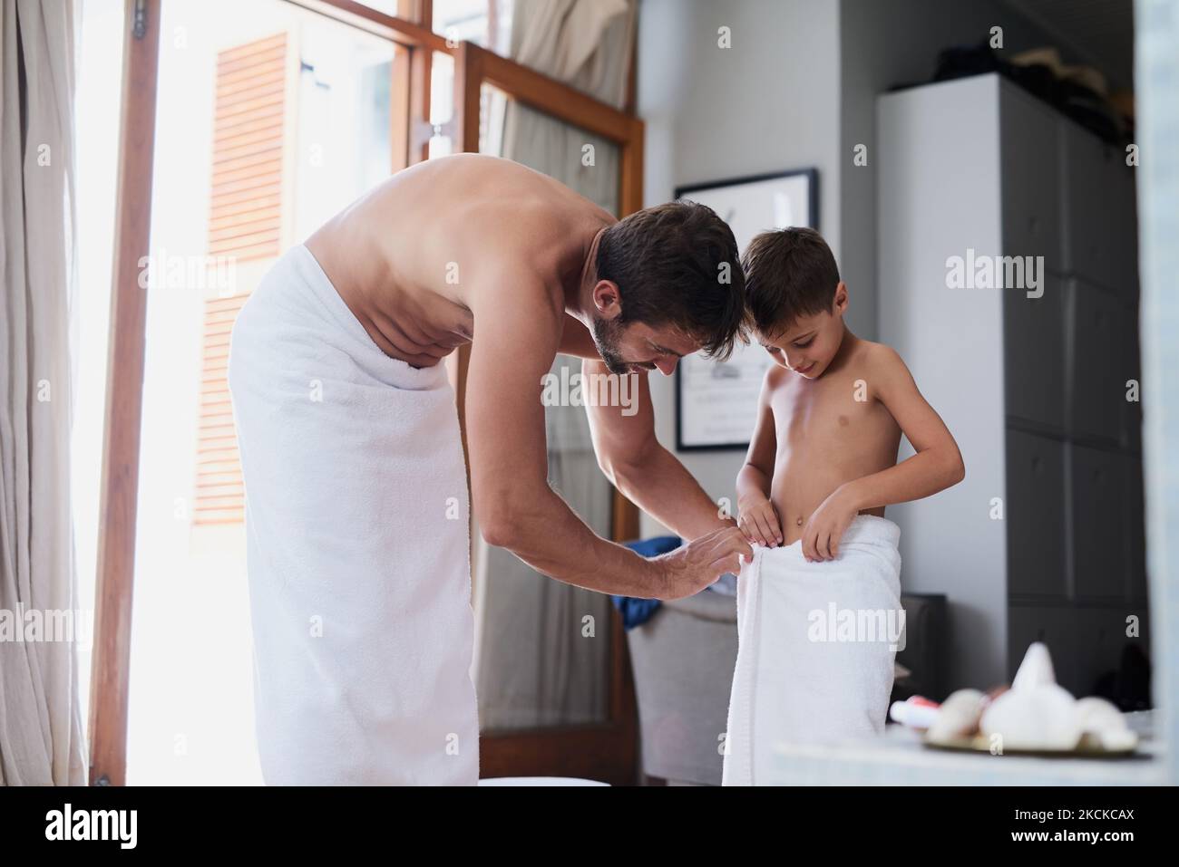 Lassen Sie mich Ihnen dabei helfen: Ein hübscher junger Mann und sein Sohn, nach einer Dusche in Handtücher eingewickelt. Stockfoto