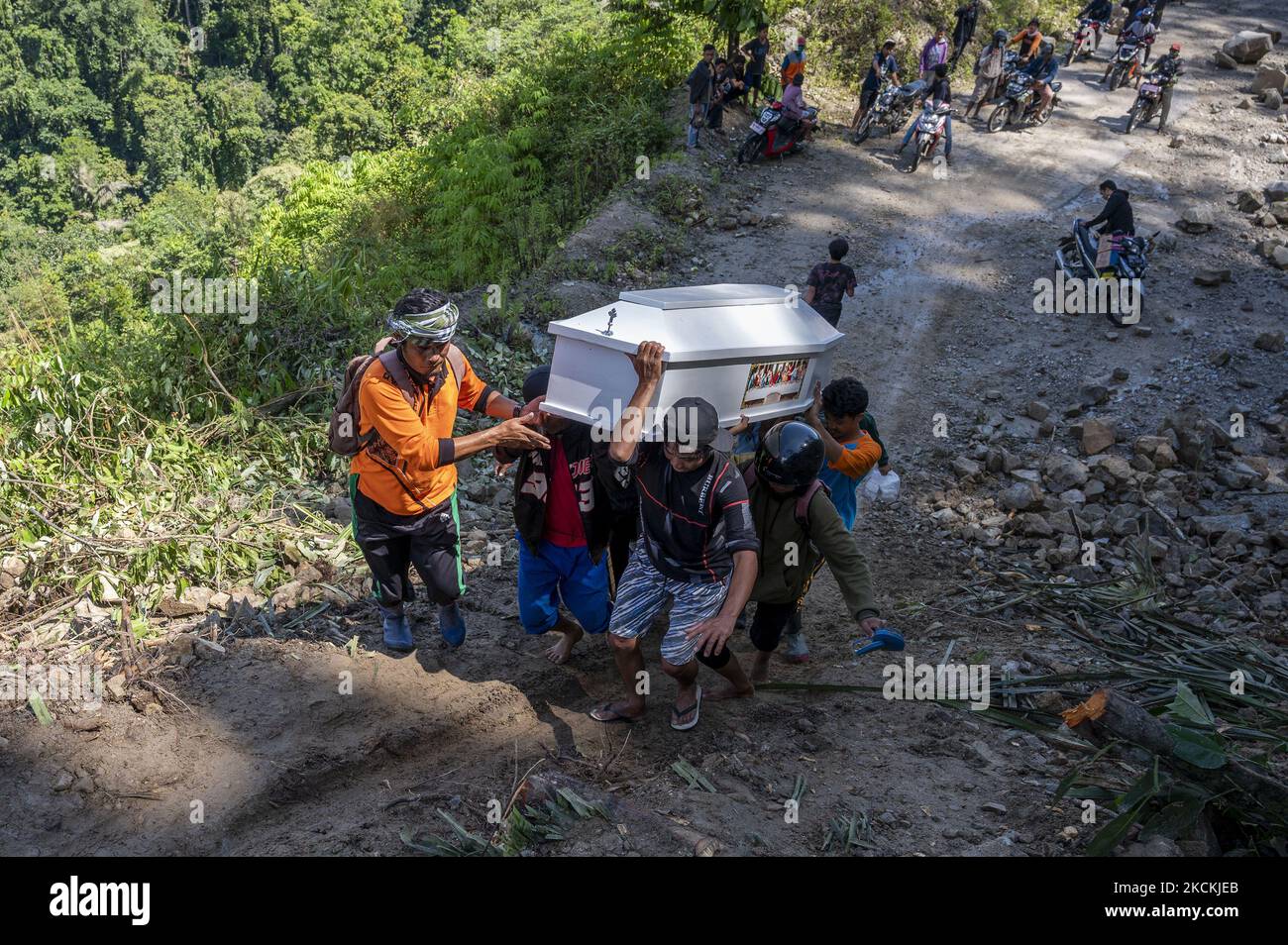 Am 31. August 2021 überqueren die Bewohner der Trans Palu-Kulawi-Straße im Dorf Salua, Sigi Regency, Provinz Zentral-Sulawesi, Indonesien, einen Sarg, der mit Erdrutschmaterial bedeckt ist. Der Leichnam wurde zur Beerdigung in sein Heimatdorf im Dorf Anca, Unterbezirk Lindu, gebracht, wo die Entfernung mehr als 25 Kilometer beträgt, da die Hauptverkehrsstraße aufgrund von Erdrutschen, die die Straße seit August 28 begraben haben, nicht von vierrädrigen Fahrzeugen überfahren werden kann. (Foto von Basri Marzuki/NurPhoto) Stockfoto