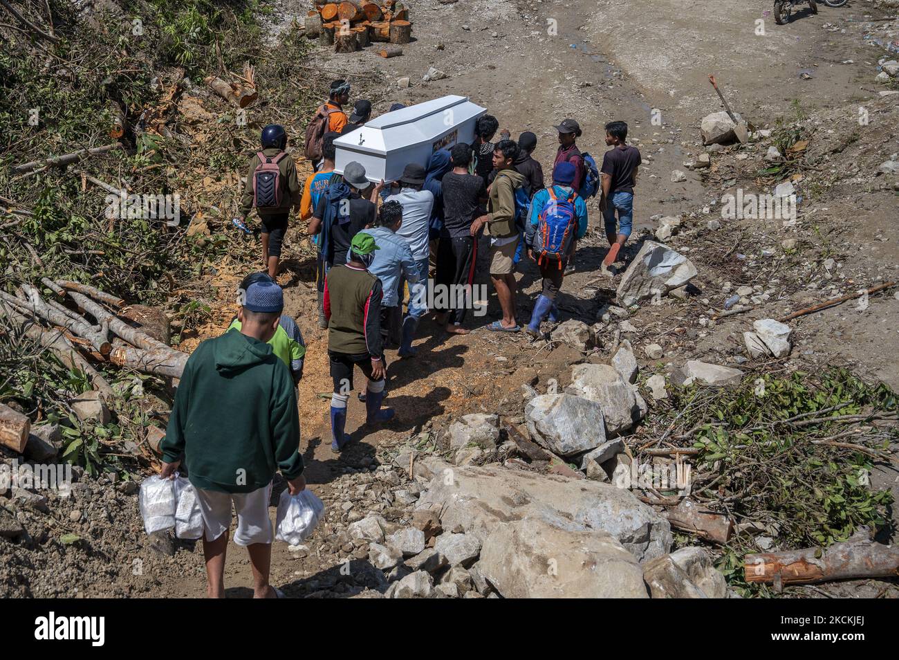 Am 31. August 2021 überqueren die Bewohner der Trans Palu-Kulawi-Straße im Dorf Salua, Sigi Regency, Provinz Zentral-Sulawesi, Indonesien, einen Sarg, der mit Erdrutschmaterial bedeckt ist. Der Leichnam wurde zur Beerdigung in sein Heimatdorf im Dorf Anca, Unterbezirk Lindu, gebracht, wo die Entfernung mehr als 25 Kilometer beträgt, da die Hauptverkehrsstraße aufgrund von Erdrutschen, die die Straße seit August 28 begraben haben, nicht von vierrädrigen Fahrzeugen überfahren werden kann. (Foto von Basri Marzuki/NurPhoto) Stockfoto