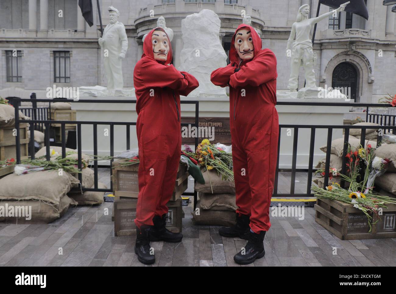 Zwei junge Männer in roten Overalls und eine Salvador Dalí Maske bewachen das Denkmal, das die 5 Gefallenen genannt wird, auf der Esplanade des Palastes der Schönen Künste in Mexiko-Stadt, vor der Premiere der fünften Staffel der Serie The House of Paper installiert. (Foto von Gerardo Vieyra/NurPhoto) Stockfoto
