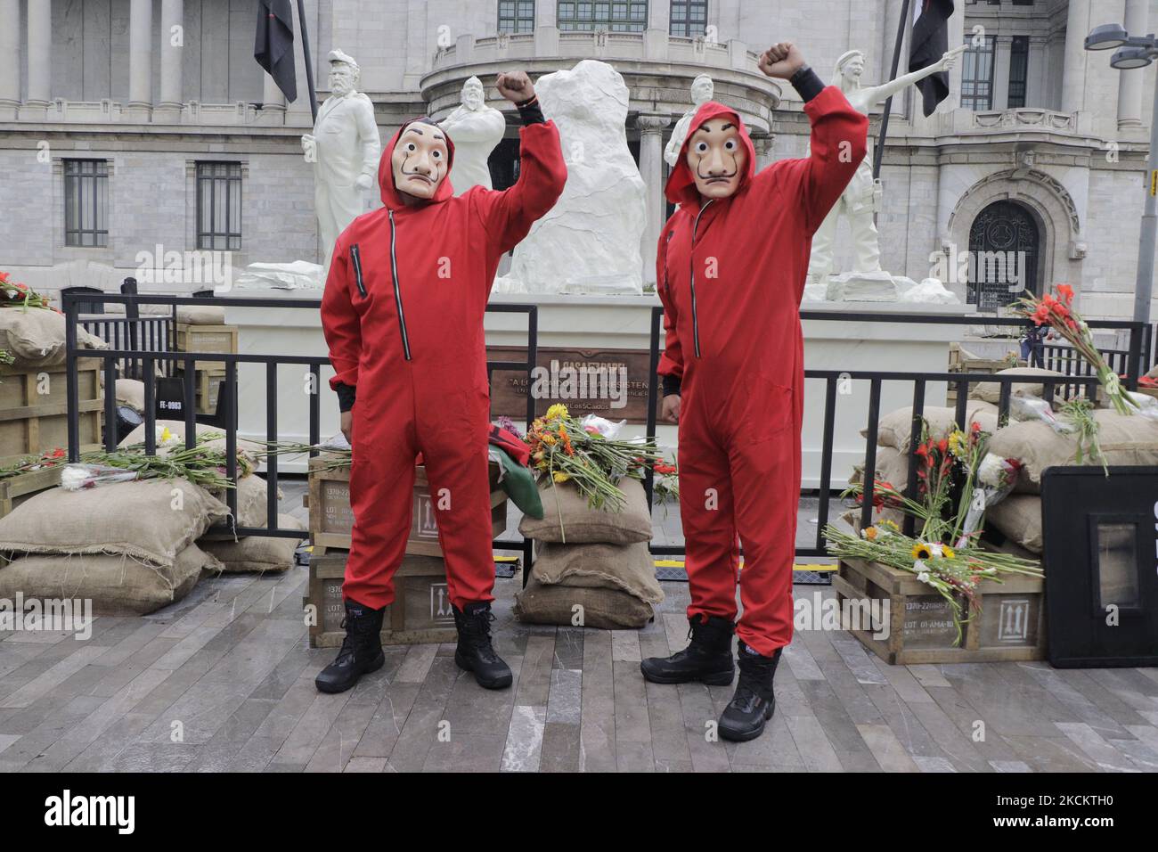 Zwei junge Männer in roten Overalls und eine Salvador Dalí Maske bewachen das Denkmal, das die 5 Gefallenen genannt wird, auf der Esplanade des Palastes der Schönen Künste in Mexiko-Stadt, vor der Premiere der fünften Staffel der Serie The House of Paper installiert. (Foto von Gerardo Vieyra/NurPhoto) Stockfoto